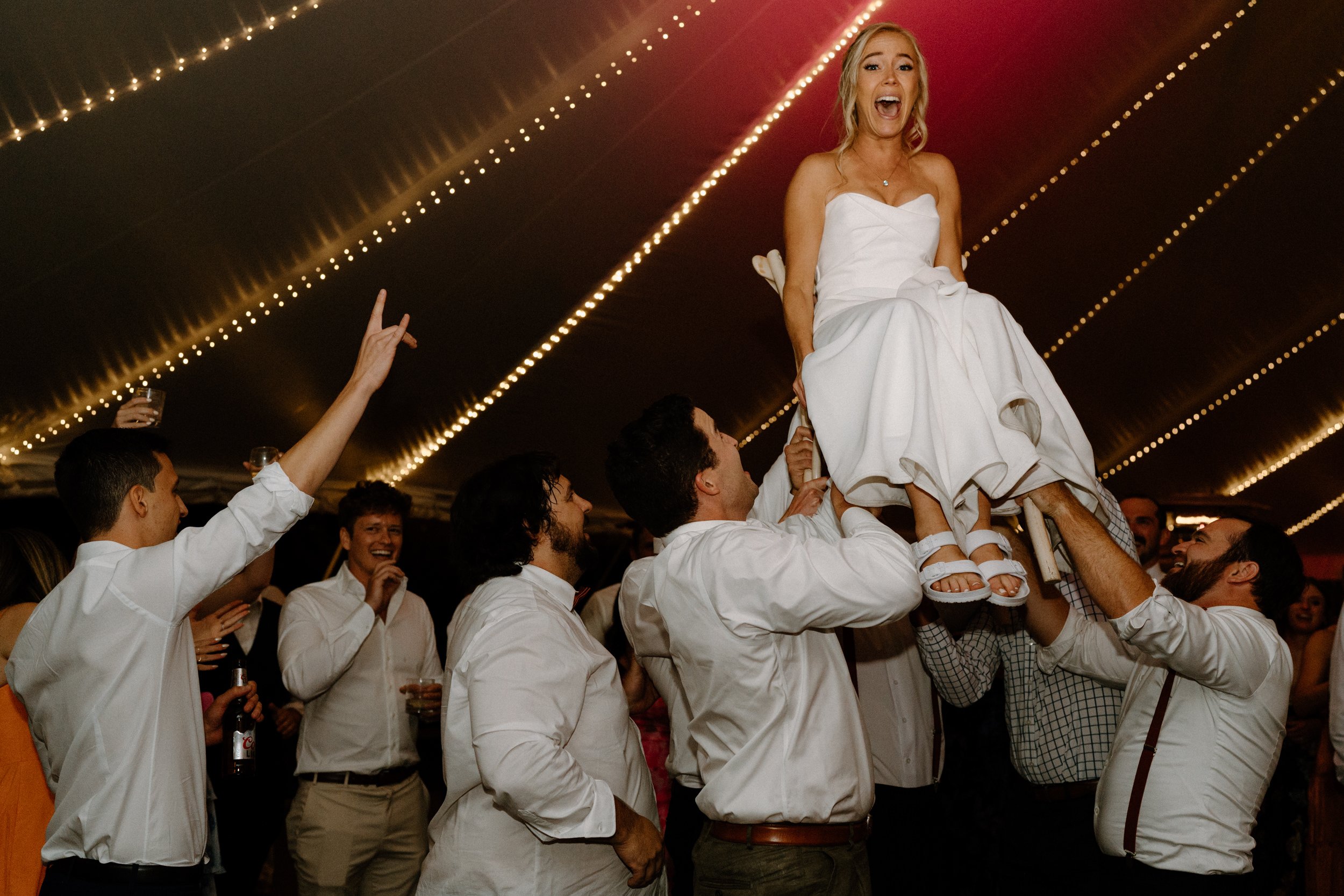 Bride on a chair being lifted by groomsmen at Blackstone Rivers Ranch