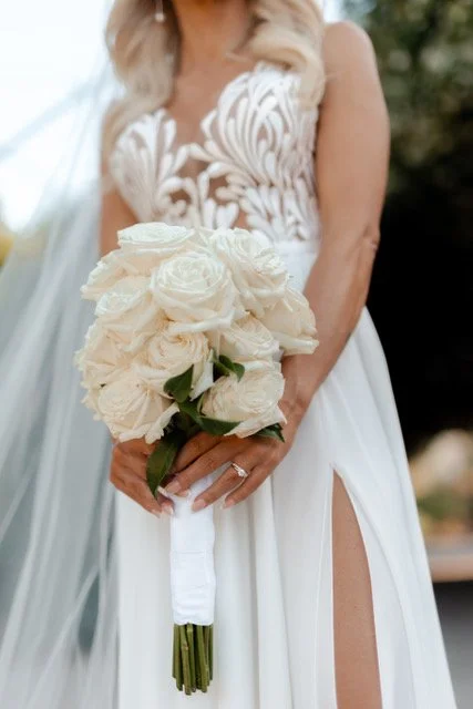 A bride holding a bouquet of off white roses