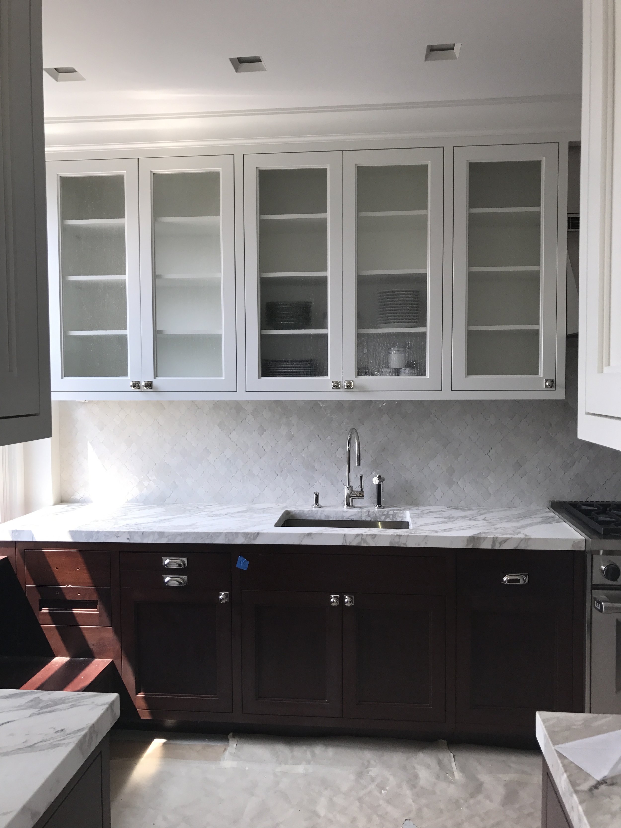  The stained oak floors are covered in this photo but otherwise it is ready to move in. We suggested building dark mahogany base cabinets with white painted upper cabinets to provide a fresh look using classic details. The glass uppers have seeded cl