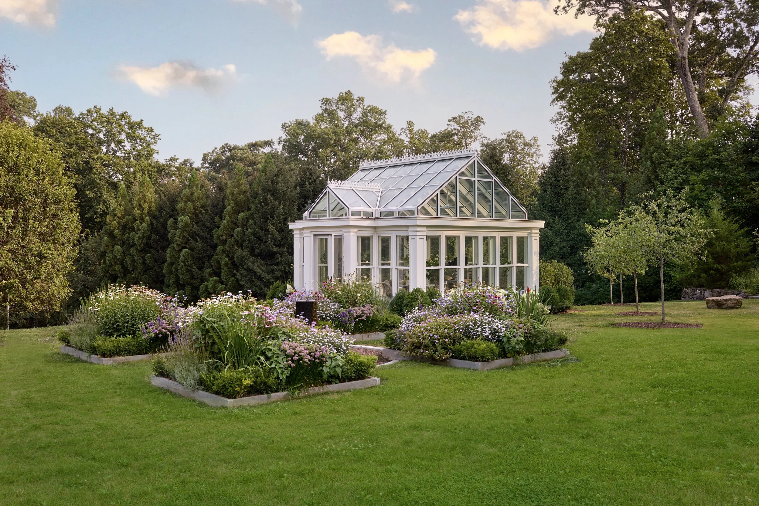  Greenhouse with raised bluestone planters hosting colorful flowers. 
