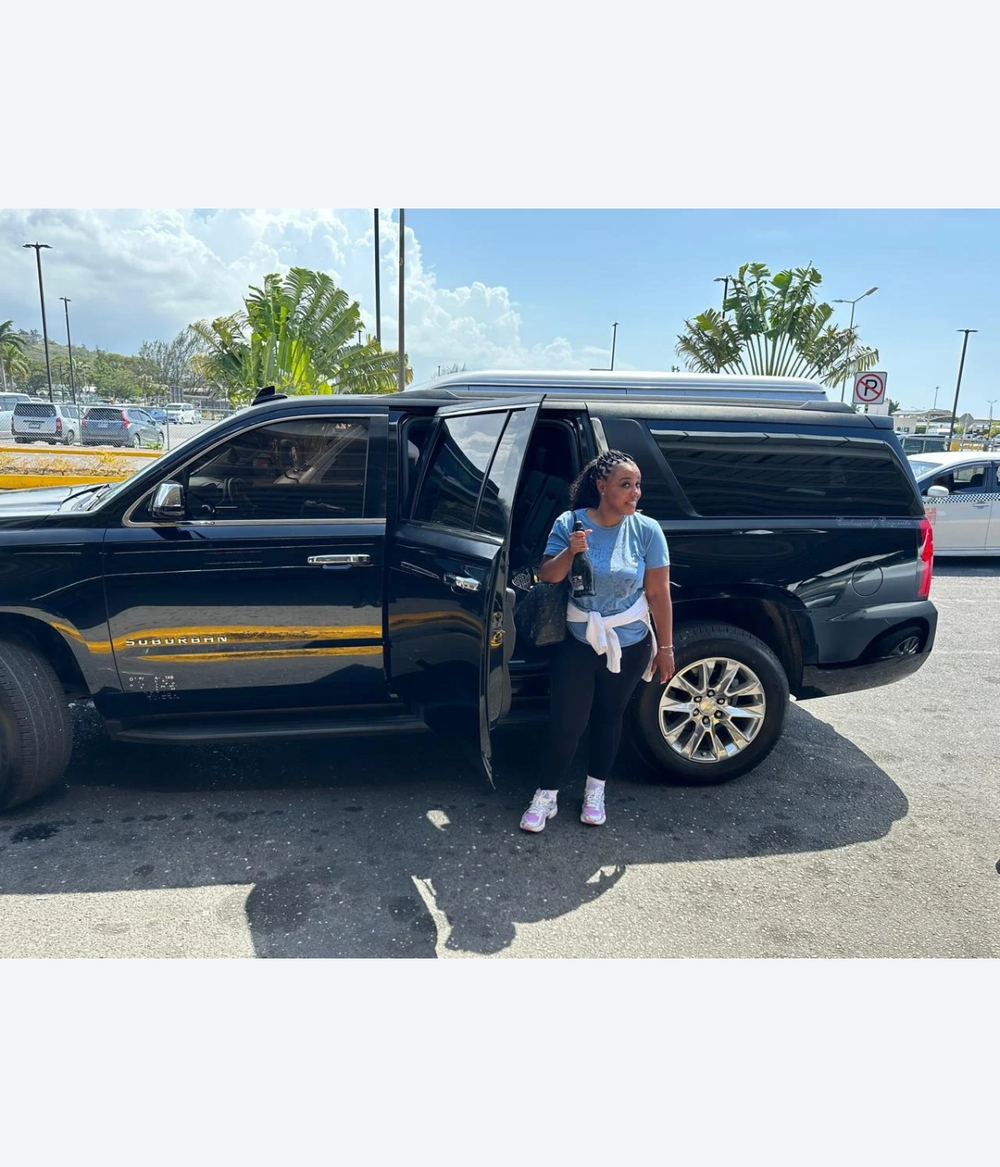 Black luxury SUV with a traveler beside it, representing VIP private transportation in Jamaica.