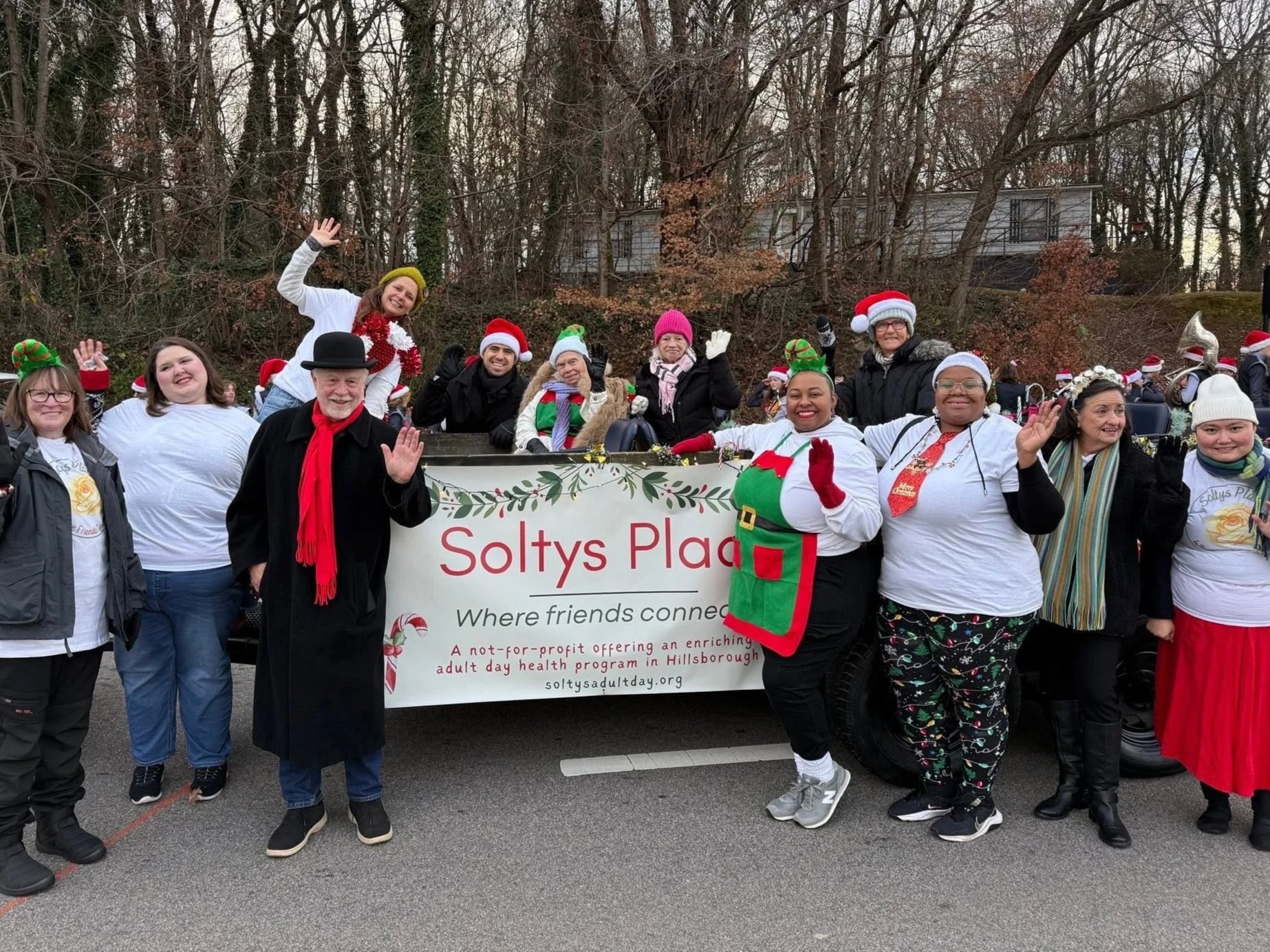 Image of people standing in Christmas costumes in front of a banner saying Soltys Place "where friends connect