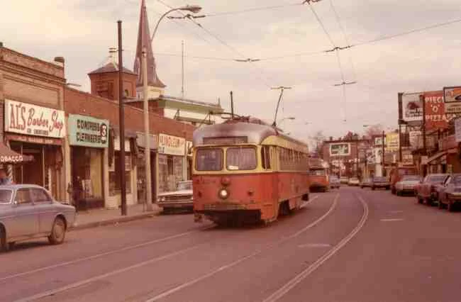 Trolley # 3328 travels down Centre Street at Seaverns Ave. on the way to the Arborway in this 1971 photo. Al's Barber Shop, Congress Cleaners, Jamaica Fruit Center, and Piece O' Pizza were all thriving businesses at the time. 