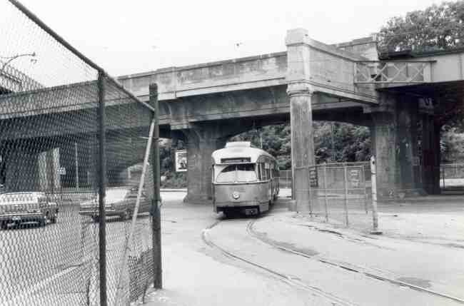 This 1968 photo shows a trolley returning to the Arborway yard while passing under the train structure on Washington Street. 