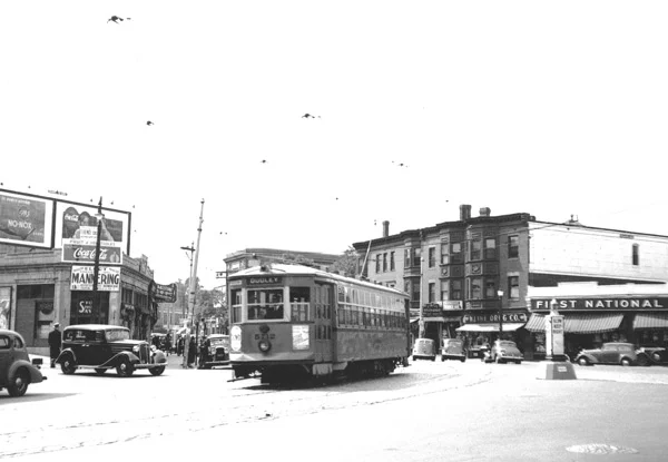 Car 5712 rounds the bend at Brigham Circle bound for Dudley Square. To the right of the car can be seen Kline Drug, Circle Restaurant, and the First National grocery store.