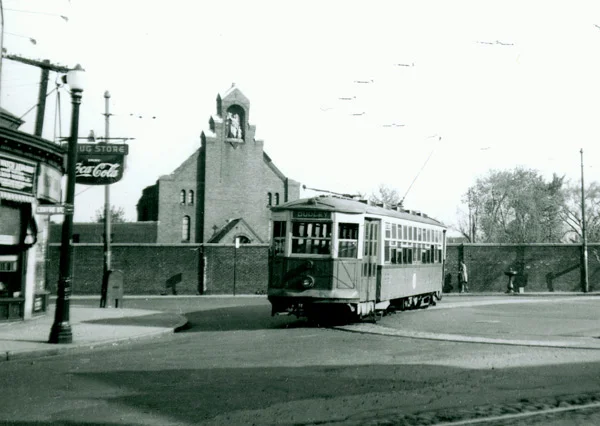 Car number 5690 makes the turnaround at Hyde Square in April of 1949. On the left can be seen a drugstore with a “Drink Coca-Cola” sign. Also on the left a sign reads “Watch Repair”. The “Centre St.” sign can also be seen clearly on the left.
A chapel can be seen behind the brick wall. Three school buildings operated by the House of Angel Guardians were also on the grounds. Photograph courtesy of Frank Cheney.
For maps and further history, see these two links:
Remember Jamaica Plain?
Bill Milhomme Blog