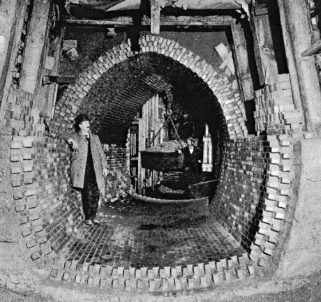  High level sewer construction in sand at Forest Hills, Jamaica Plain.&nbsp; Note bin suspended from overhead crane with trolley used to remove excavated dirt from tunnel. Due to the sandy nature of the soil in this area, wooden beams resting on a fo