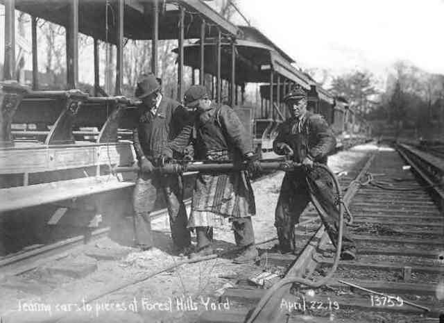Workmen using a pneumatic impact wrench dismantle open air trolley cars at the Forest Hills yard in 1919. Courtesy of Anthony Sammarco.
