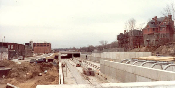 The Orange Line's new Green St. station under construction. On the left in the foreground is Amory Street and English High School. On the right, the rear of homes on Everett St. are shown.