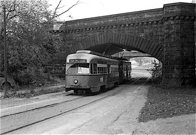 Inbound Green Line streetcar and the Forest Hills viaduct about 1980. The Elevated balustrade can be glimpsed in the background. Not a square inch in this photograph remains today. Jamaica Plain Historical Society.

