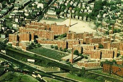 An aerial view of Bromley Heath taken in April 1977. The Lowell Estate stretched from Centre Street, on the far right, to the ridgeline of the housing cornices. The smokestack in the background is all that remains of the Plant Shoe factory that burned on February 2, 1976.