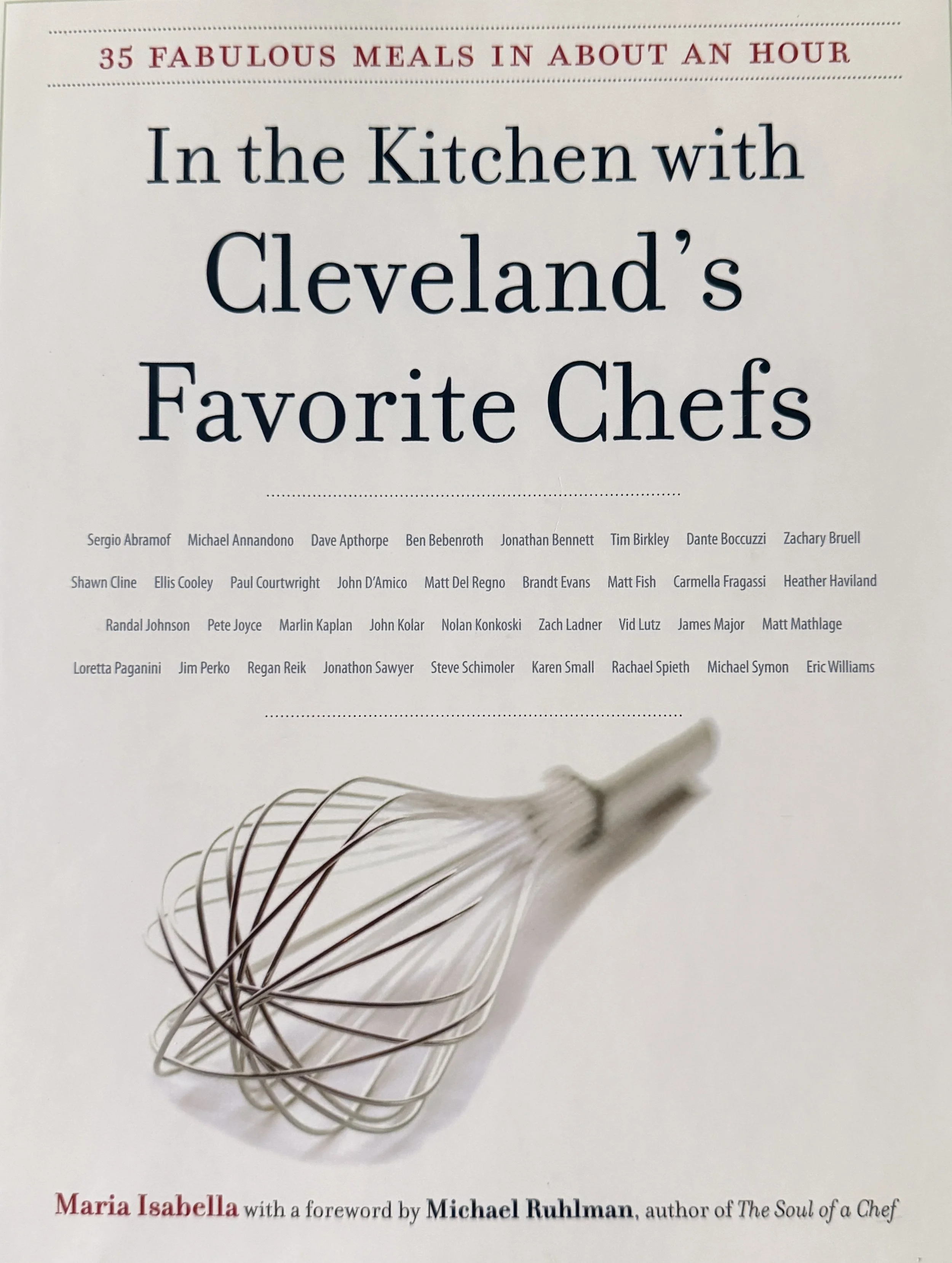 Book cover titled "In the Kitchen with Cleveland's Favorite Chefs," featuring a whisk on a white background with a list of chef names below.