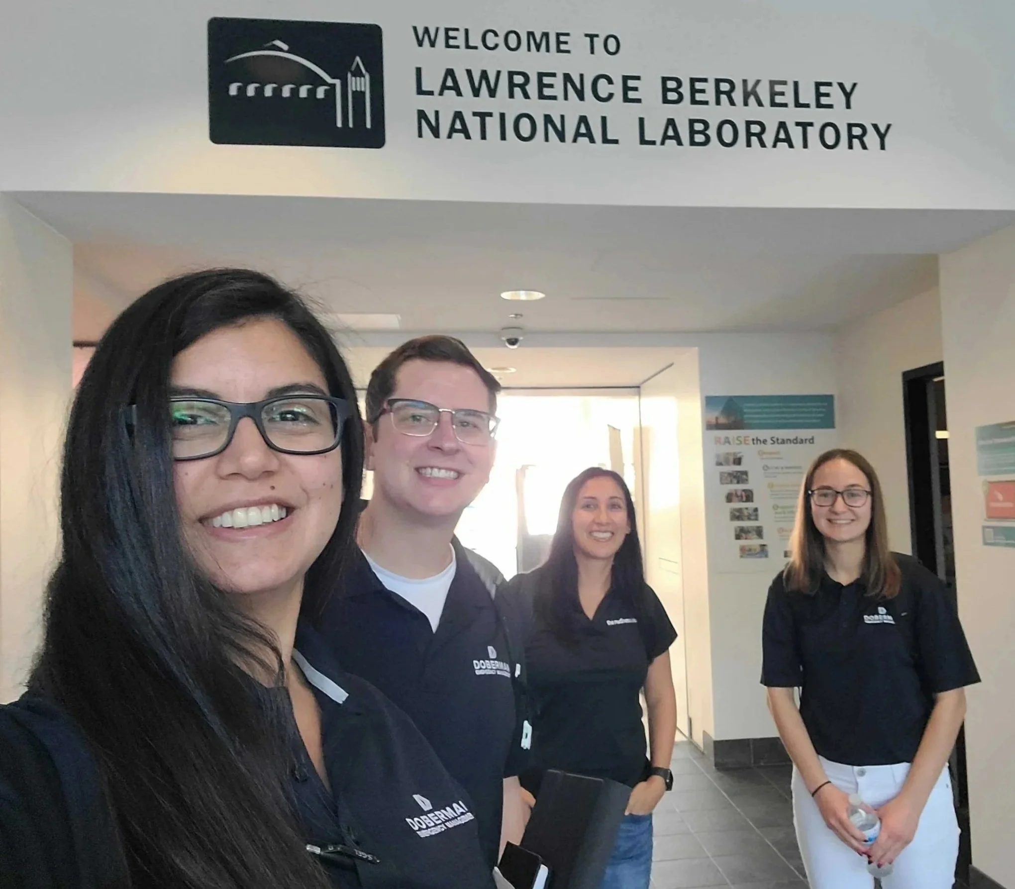 Doberman employees standing in a hallway near a sign that reads "Welcome to Lawrence Berkeley National Laboratory" doing on-site risk assessments.