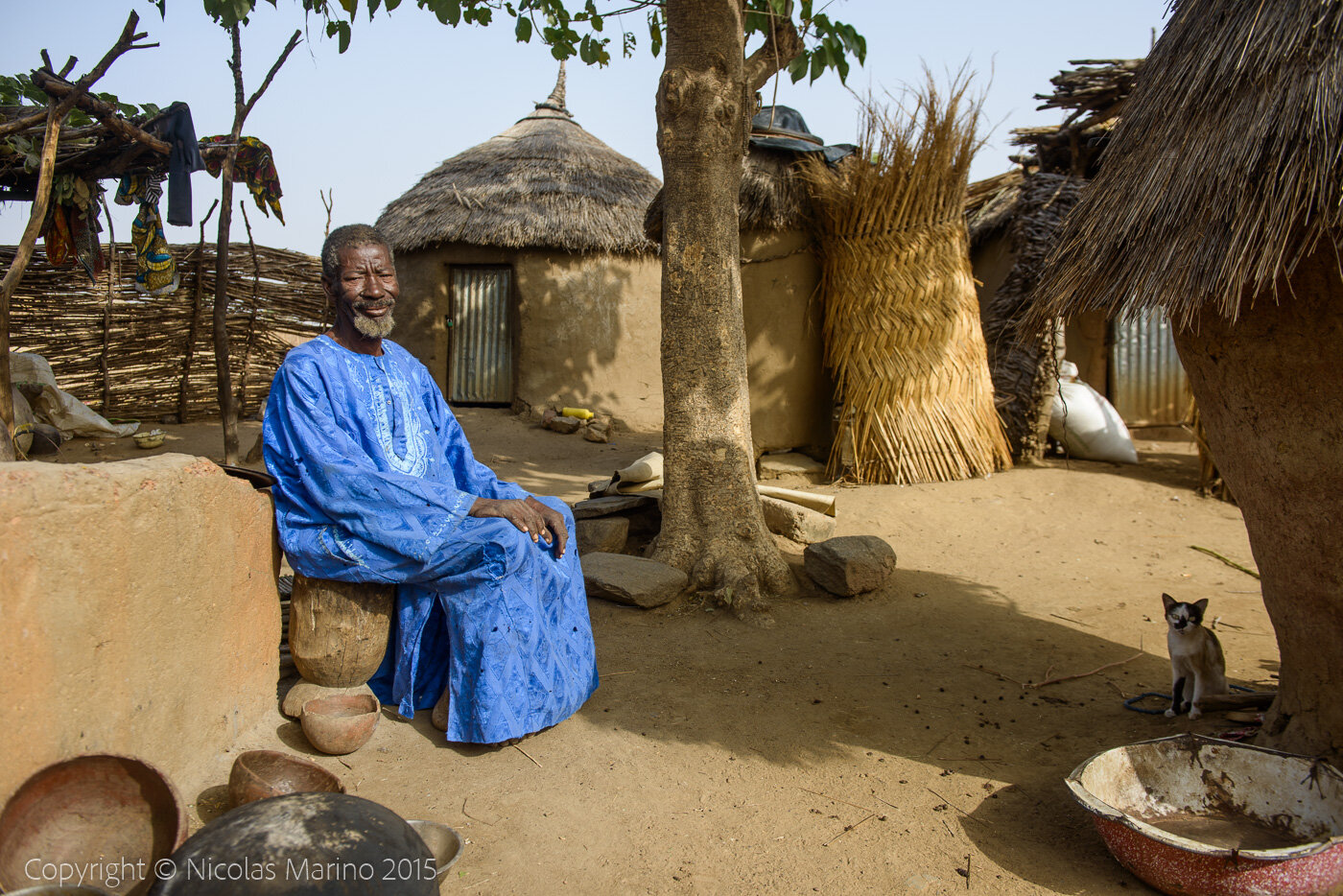 A Burkinabe man in his village, cutting pumpkins to turn them into drinking and eating containers. Burkina Faso