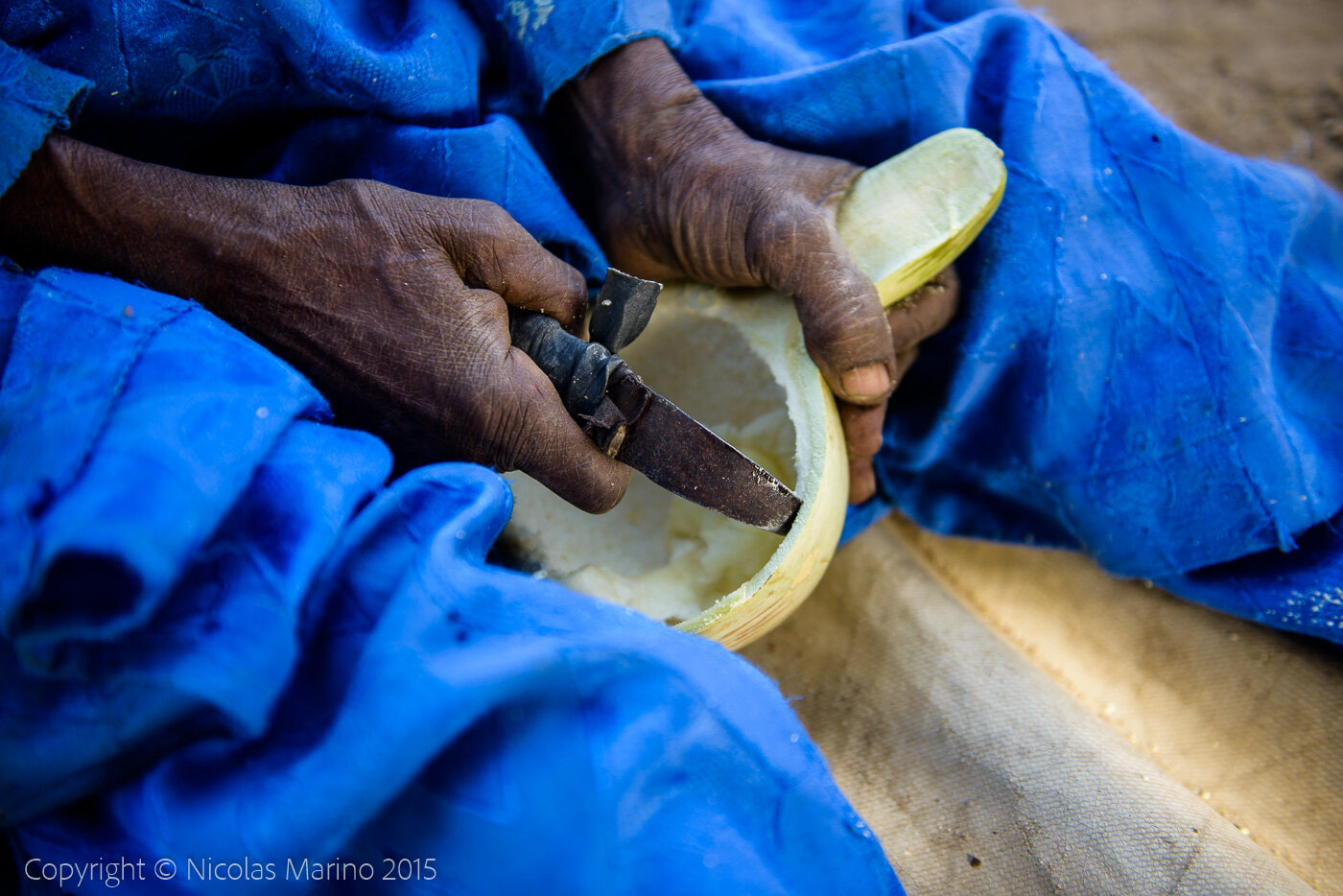 A Burkinabe man in his village, cutting pumpkins to turn them into drinking and eating containers. Burkina Faso