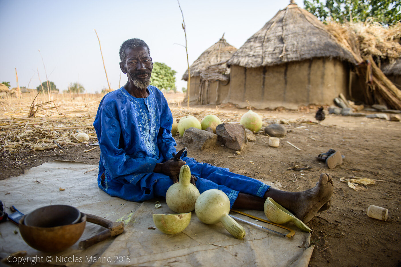 A Burkinabe man in his village, cutting pumpkins to turn them into drinking and eating containers. Burkina Faso