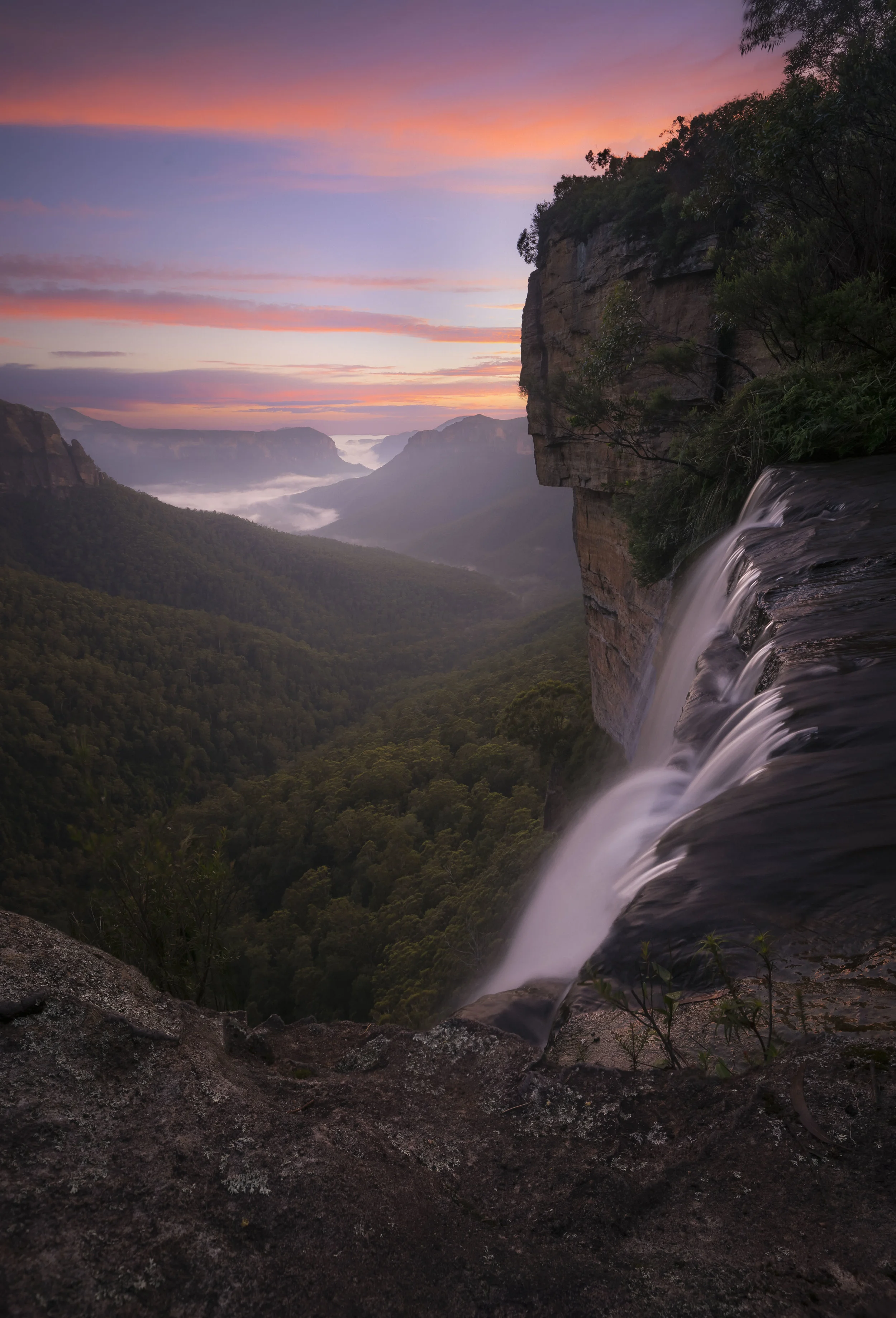 Govetts Leap Falls cascading down a cliff surrounded by forested terrain