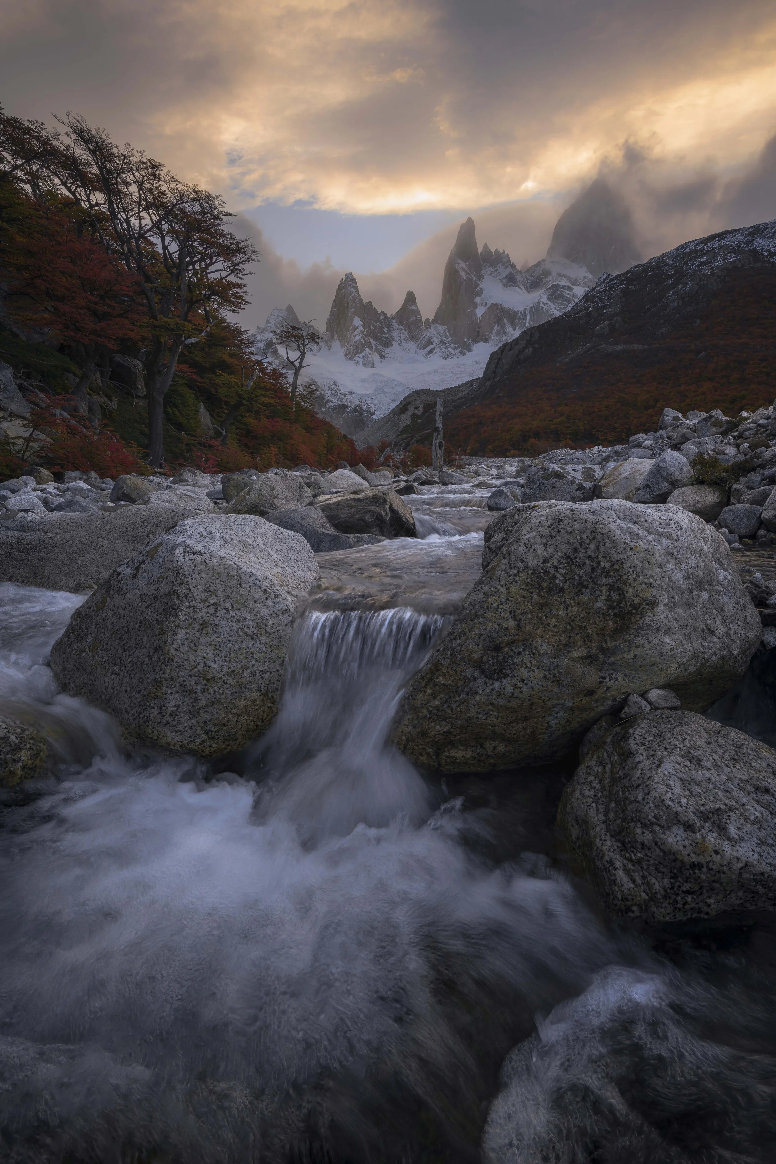 Small waterfall in the foreground with Mount Fitz Roy illuminated by the warm light of sunset