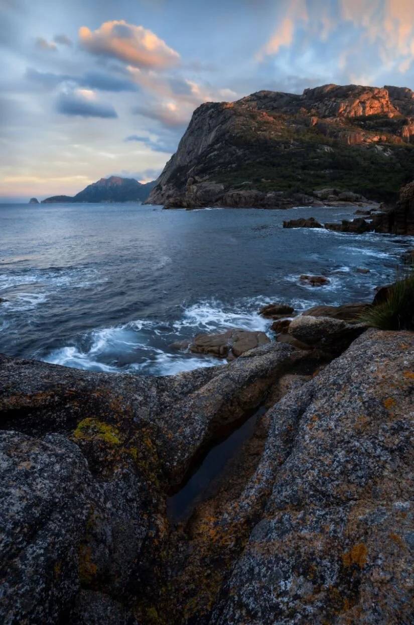 Freycinet National Park in Tasmania at sunset, highlighting coastal cliffs, beaches, and vibrant sky over the ocean