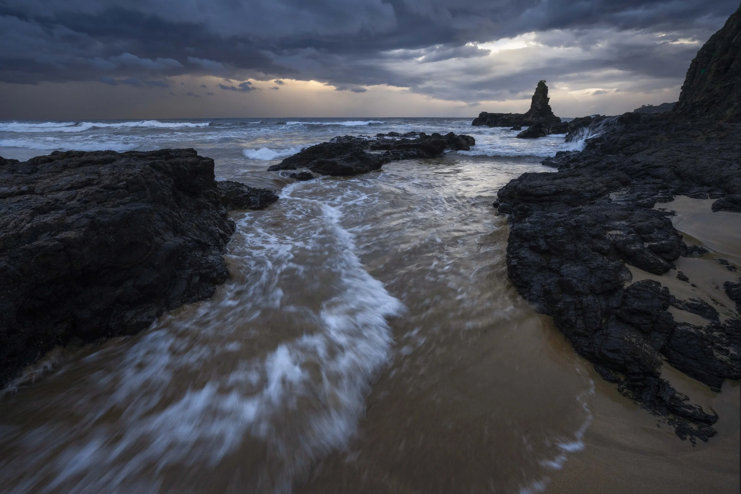 Moody sunrise over Cathedral Rocks with waves crashing along the coastline