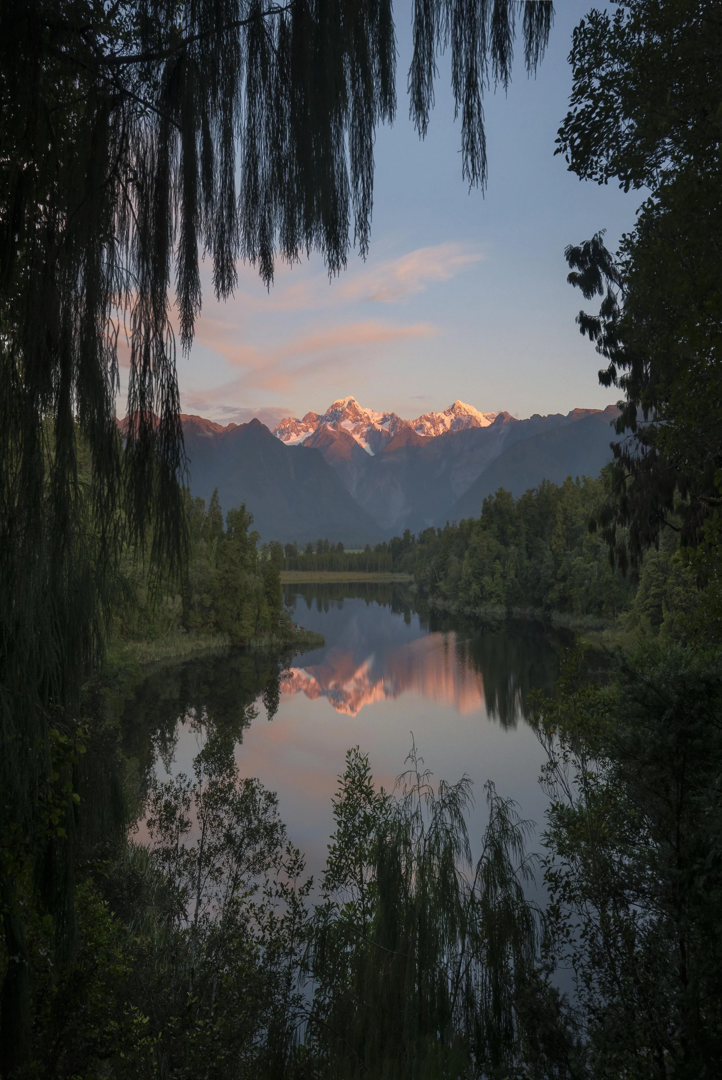 Calm waters of Lake Matheson reflecting surrounding mountains and forest