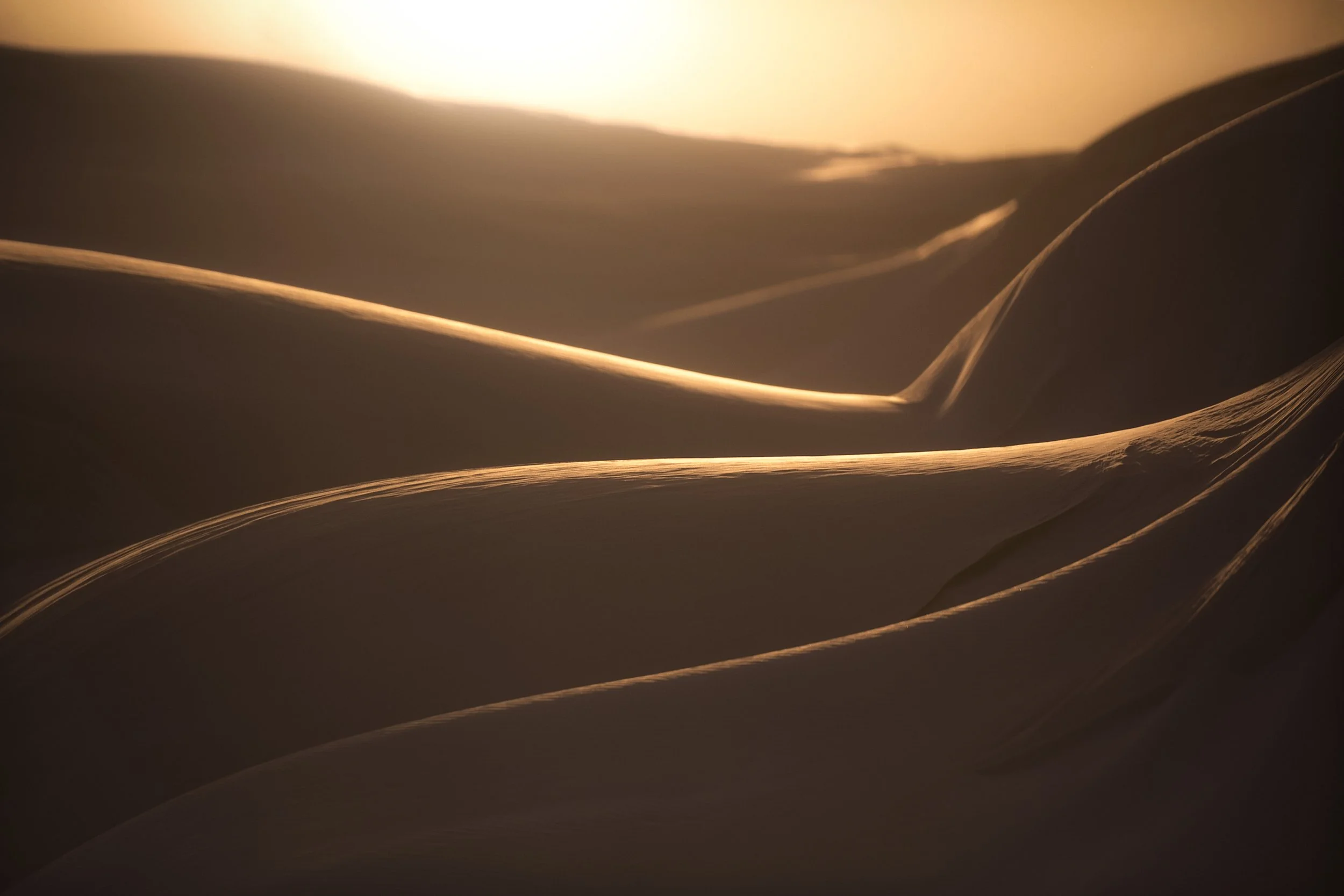 Sunlight casting shadows and patterns across sand dunes