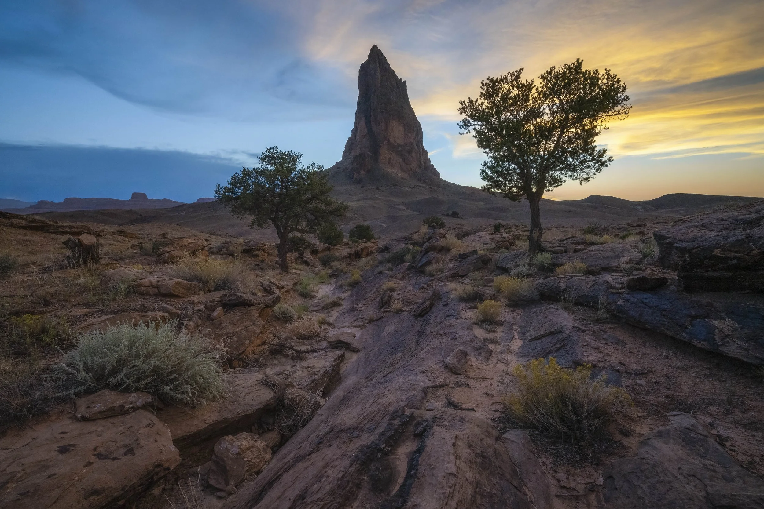 Agathlan Peak in Arizona, USA, at sunset, showing desert terrain, rock formations, and vibrant sky colours
