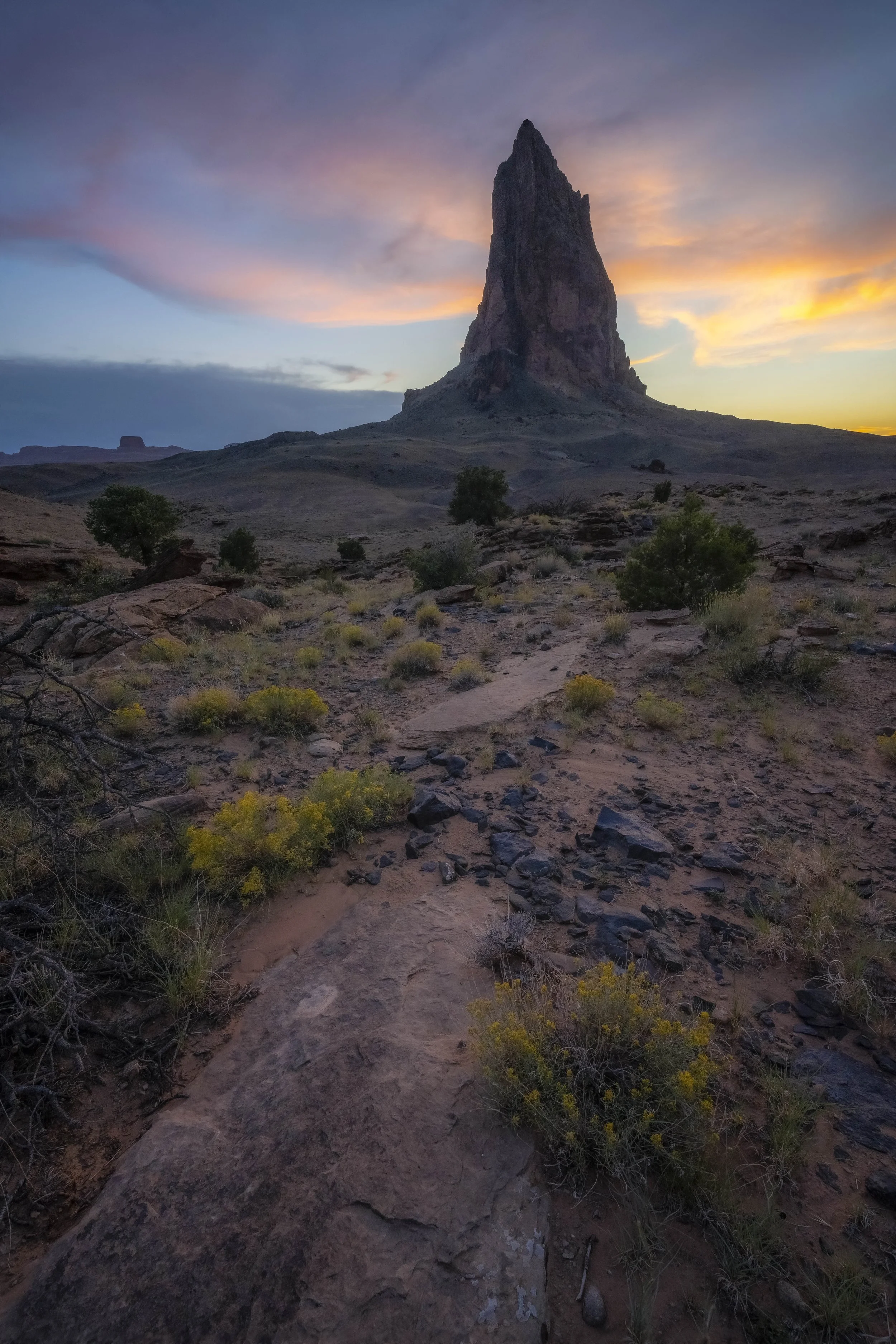 Sunset illuminating Agathlan Peak with desert landscape and rugged rock formations in warm golden light