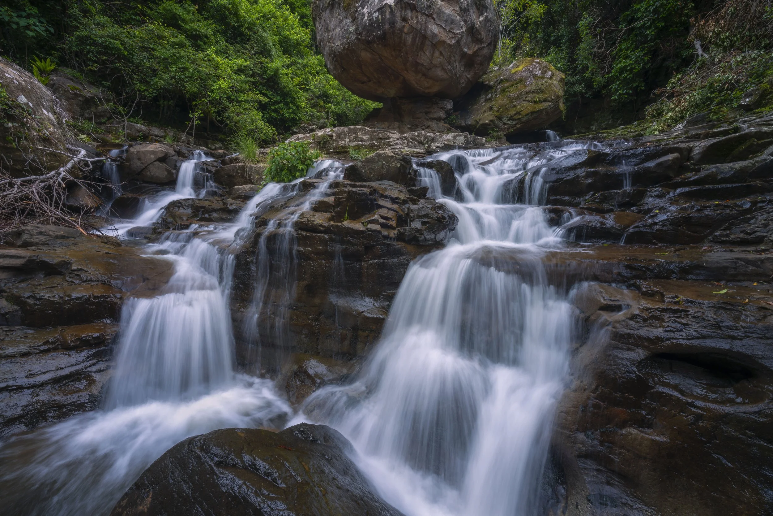Powerful waterfall cascading around a prominent boulder