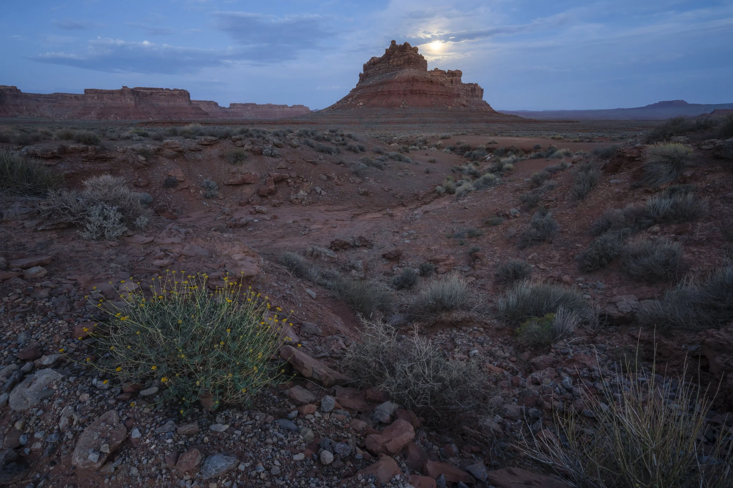 Full moon illuminating a red rock formation in Utah, USA, highlighting the desert cliffs and terrain under night sky