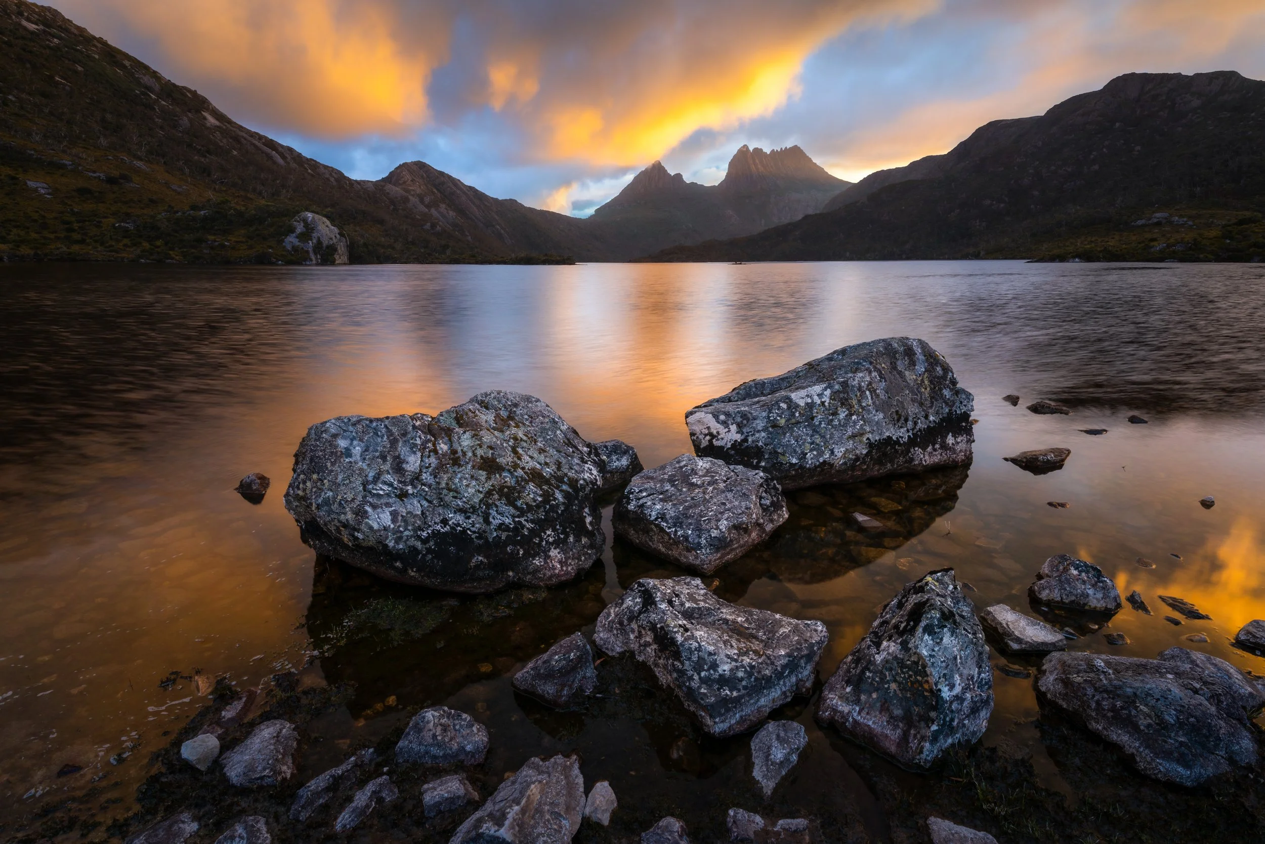 Cradle Mountain illuminated by a vibrant sunset with colorful sky reflecting on alpine lake