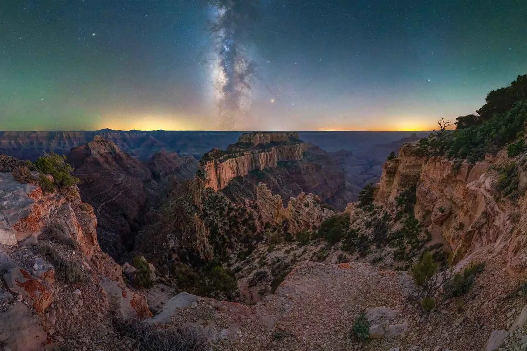 The Milky Way glows over the rocky cliffs and deep valleys of the Grand Canyon under a clear night sky