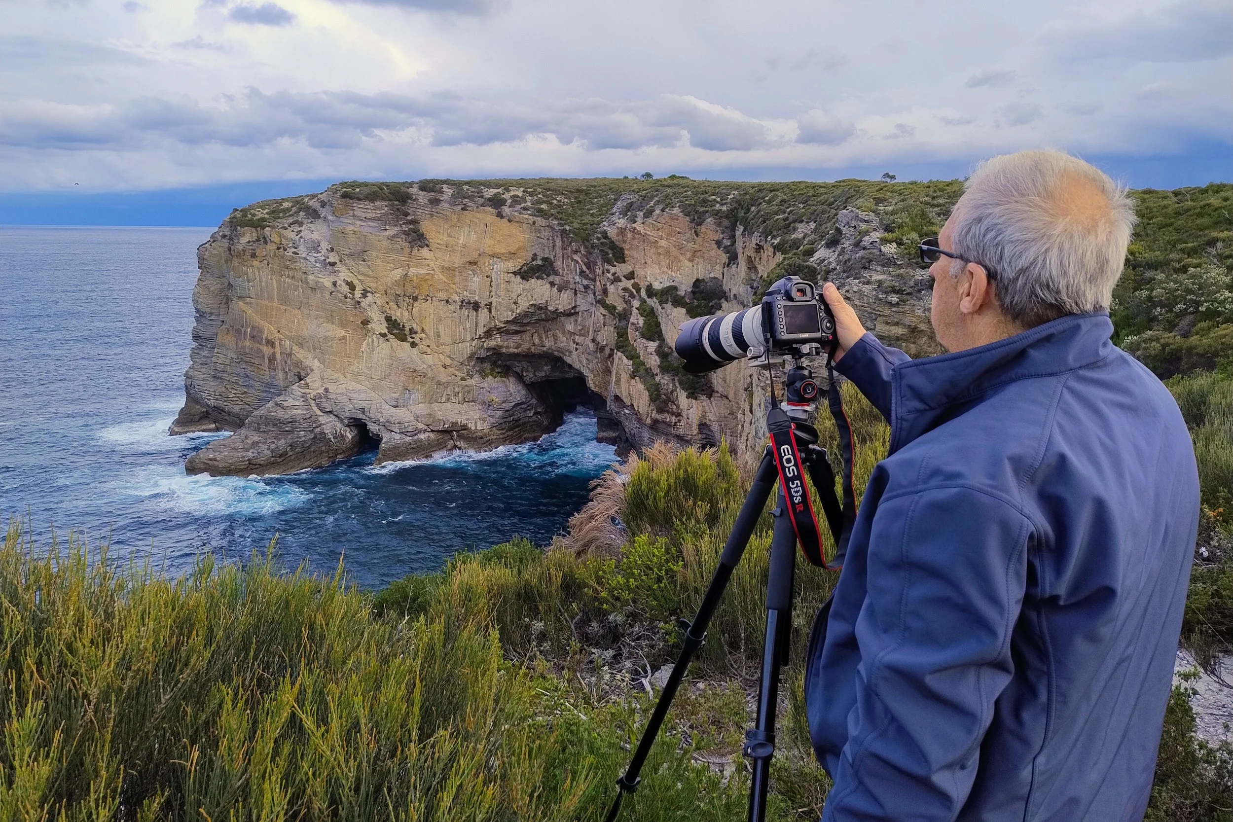 Workshop participant taking a photo over an ocean cliff