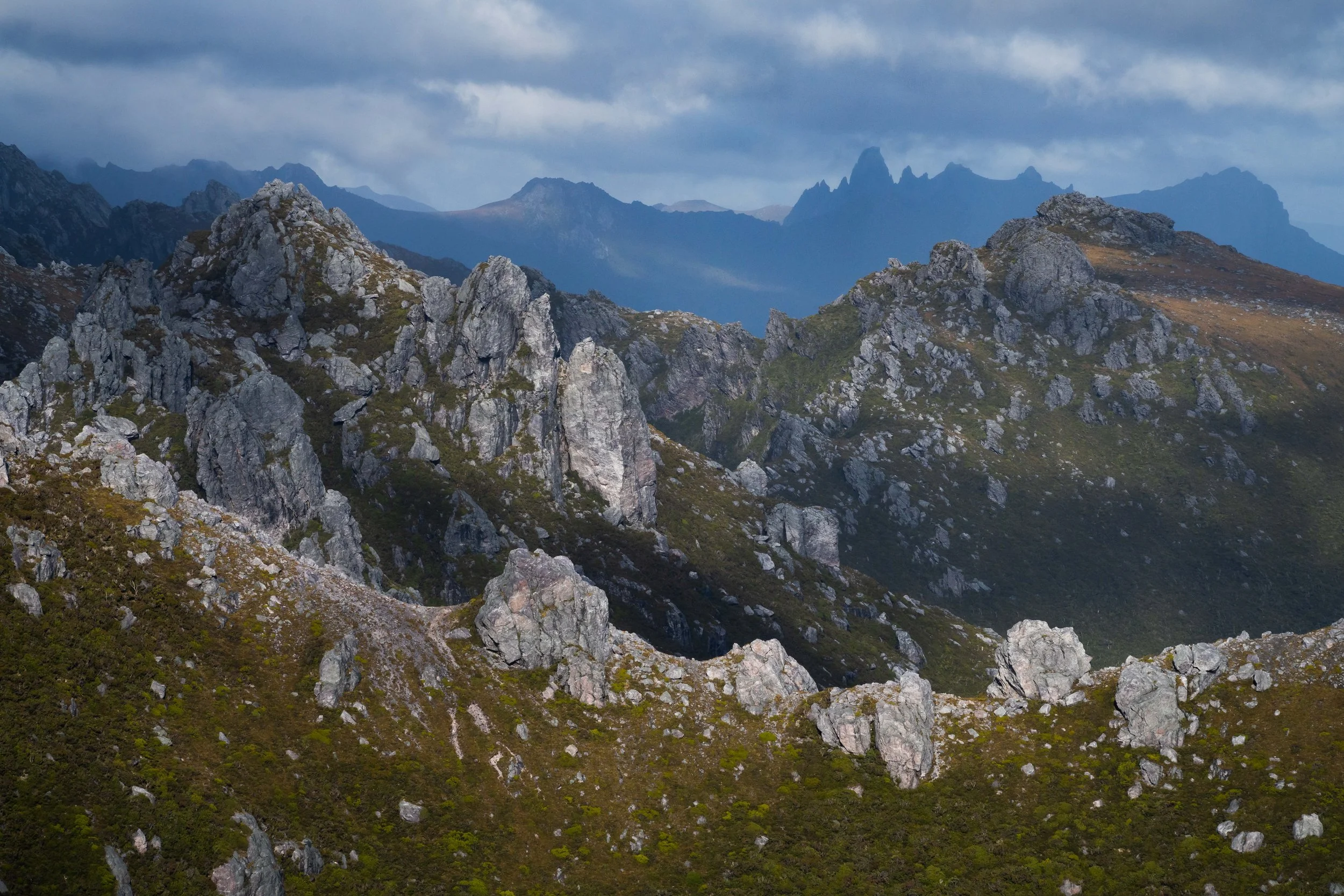 Federation Peak rising above layered ridges and valleys, with atmospheric perspective creating visible depth