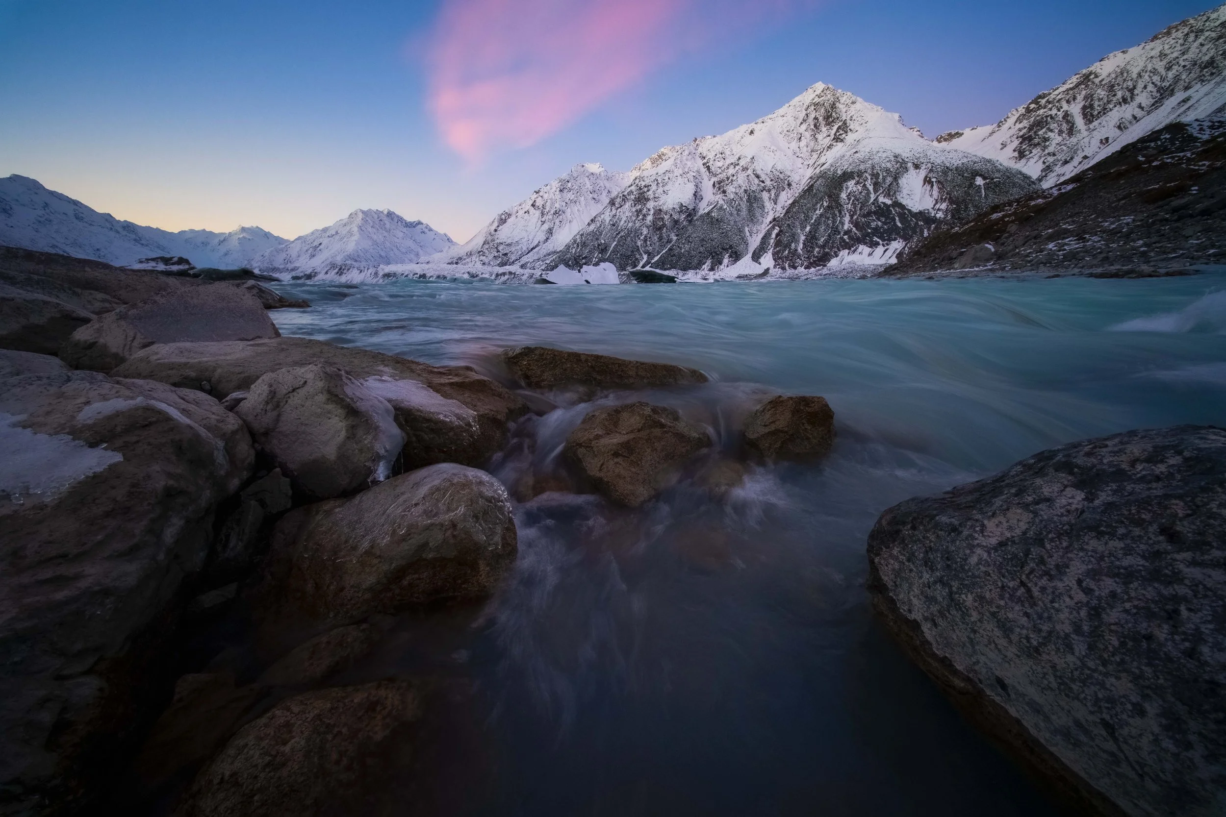 Tasman Lake in Aoraki / Mount Cook National Park, New Zealand, with floating icebergs, turquoise glacial water, and snow-covered mountains in the background.
