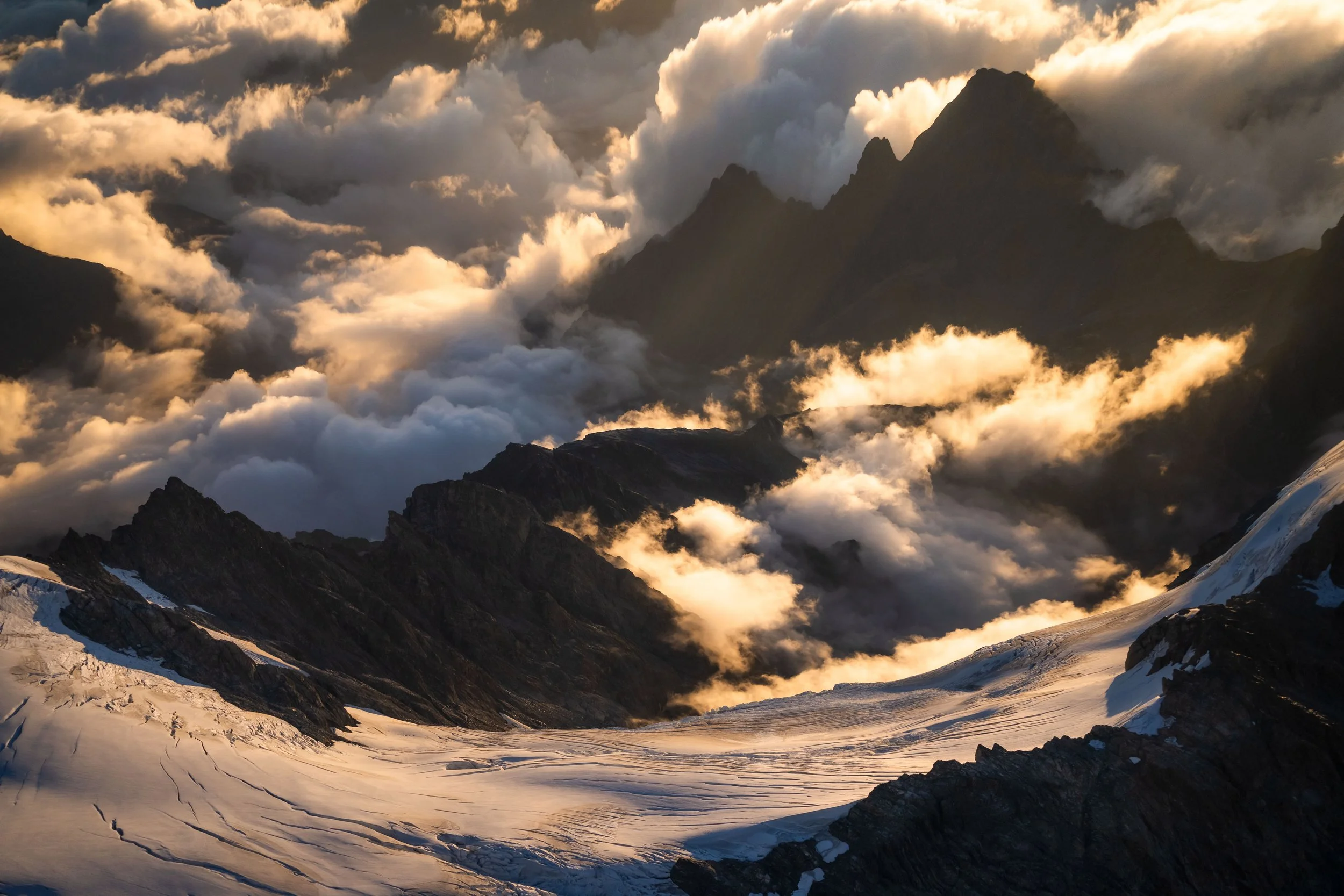 Dramatic aerial photograph of New Zealand’s Southern Alps at sunset, highlighting mountain ridges and golden light