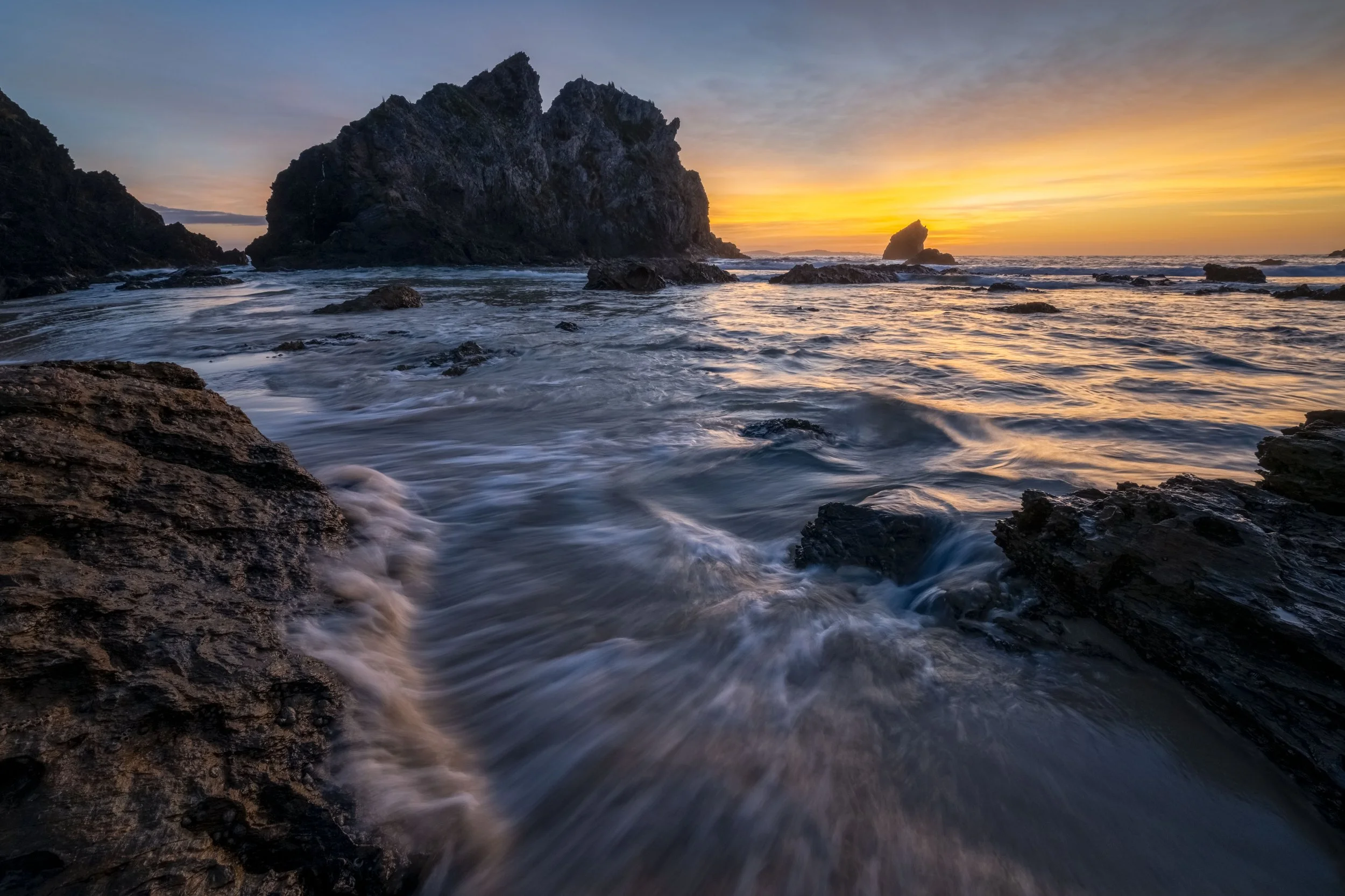 Sunlight reflecting on the water near a sea stack at Narooma during sunrise