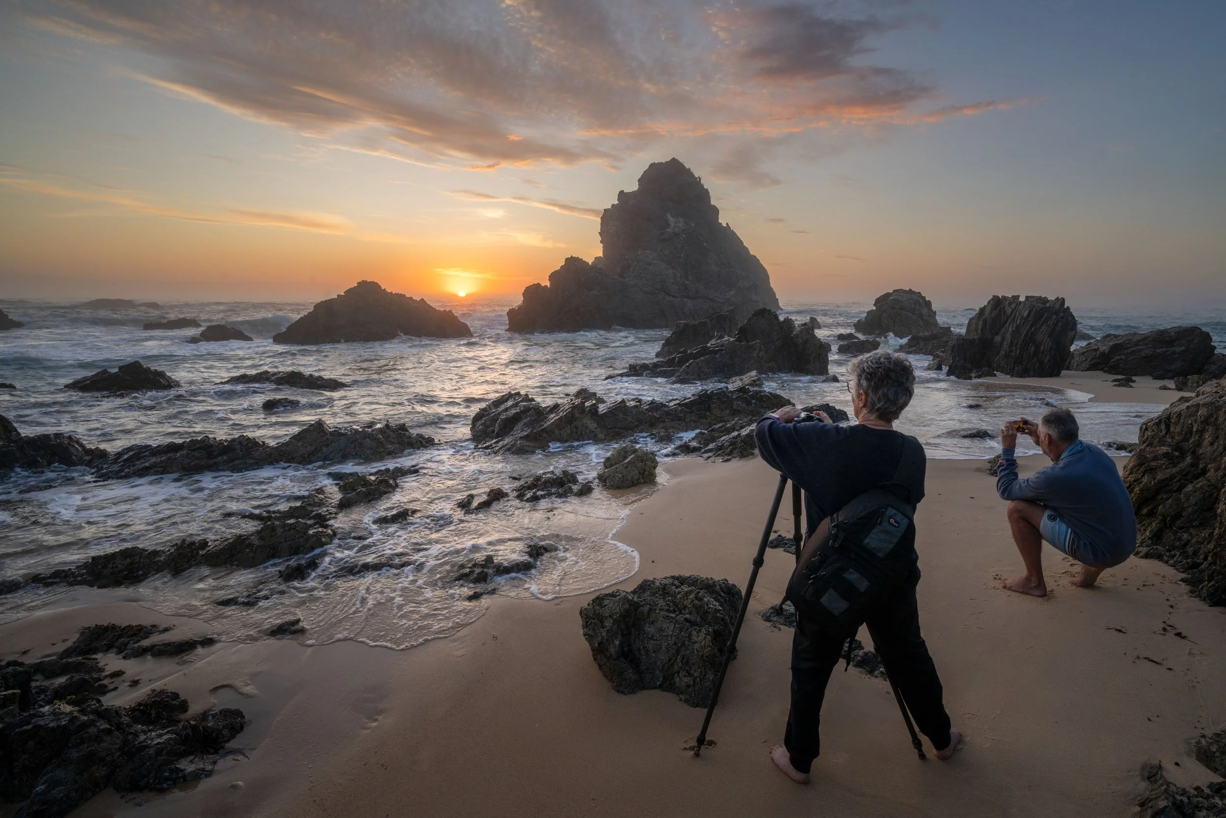 Photography workshop participants taking images of a vibrant sunrise next to the ocean