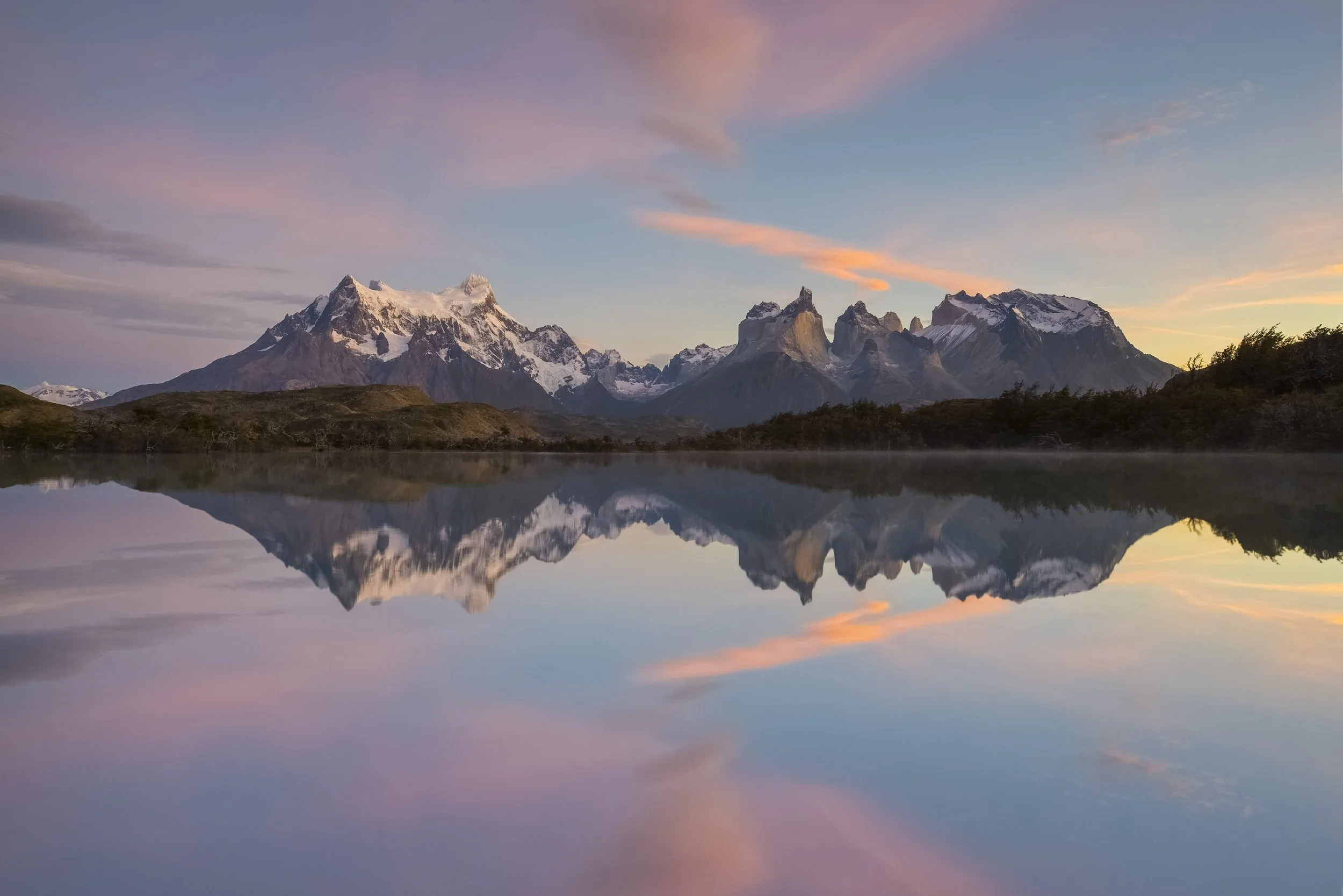 Soft pastel sunrise over Torres del Paine in Patagonia, Chile, with mountains mirrored in a still lake