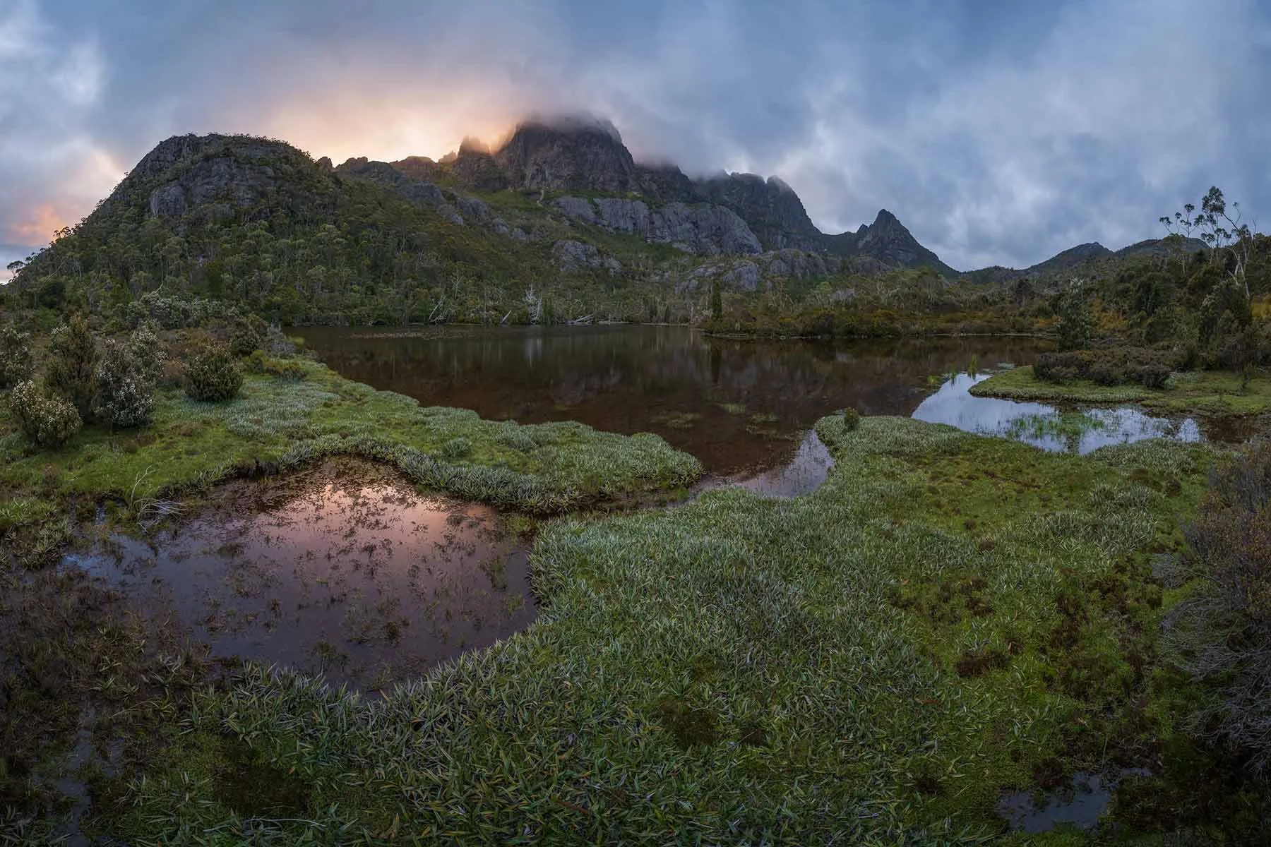 Cradle Mountain illuminated by warm sunset light, with surrounding alpine landscape and lakes