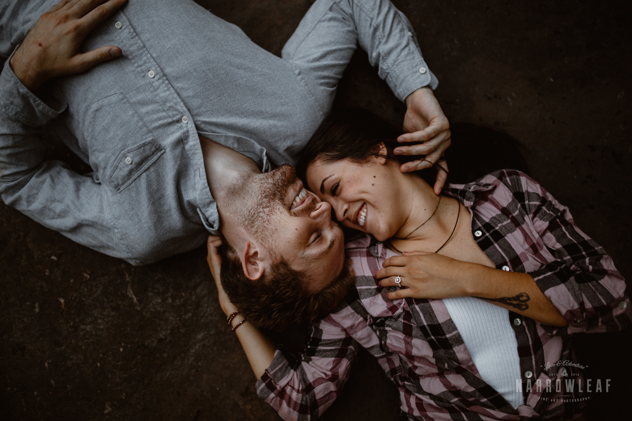Engaged couple laying on their backs by the river in Minnesota