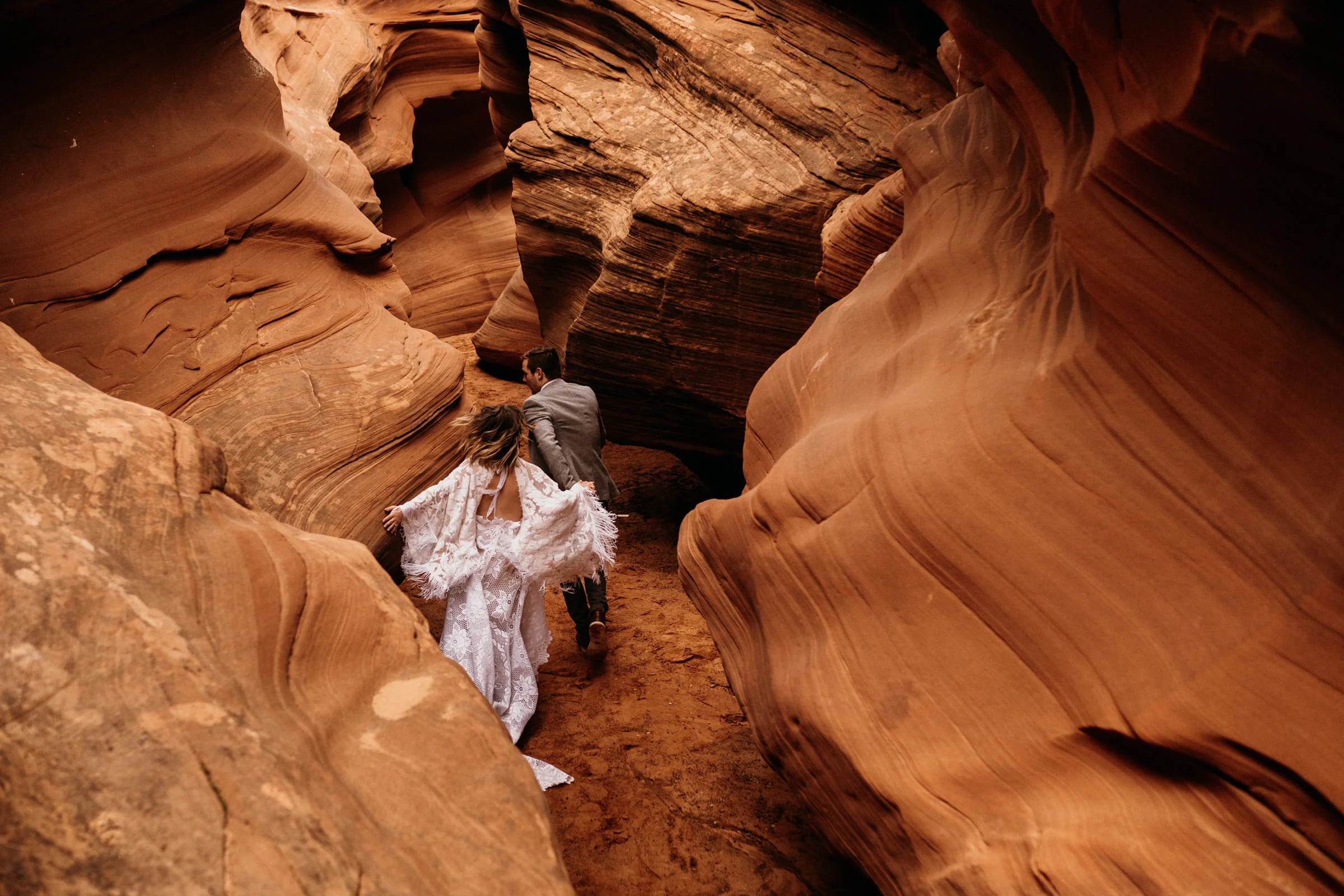 eloping-couple-running-through-slot-canyon.jpg