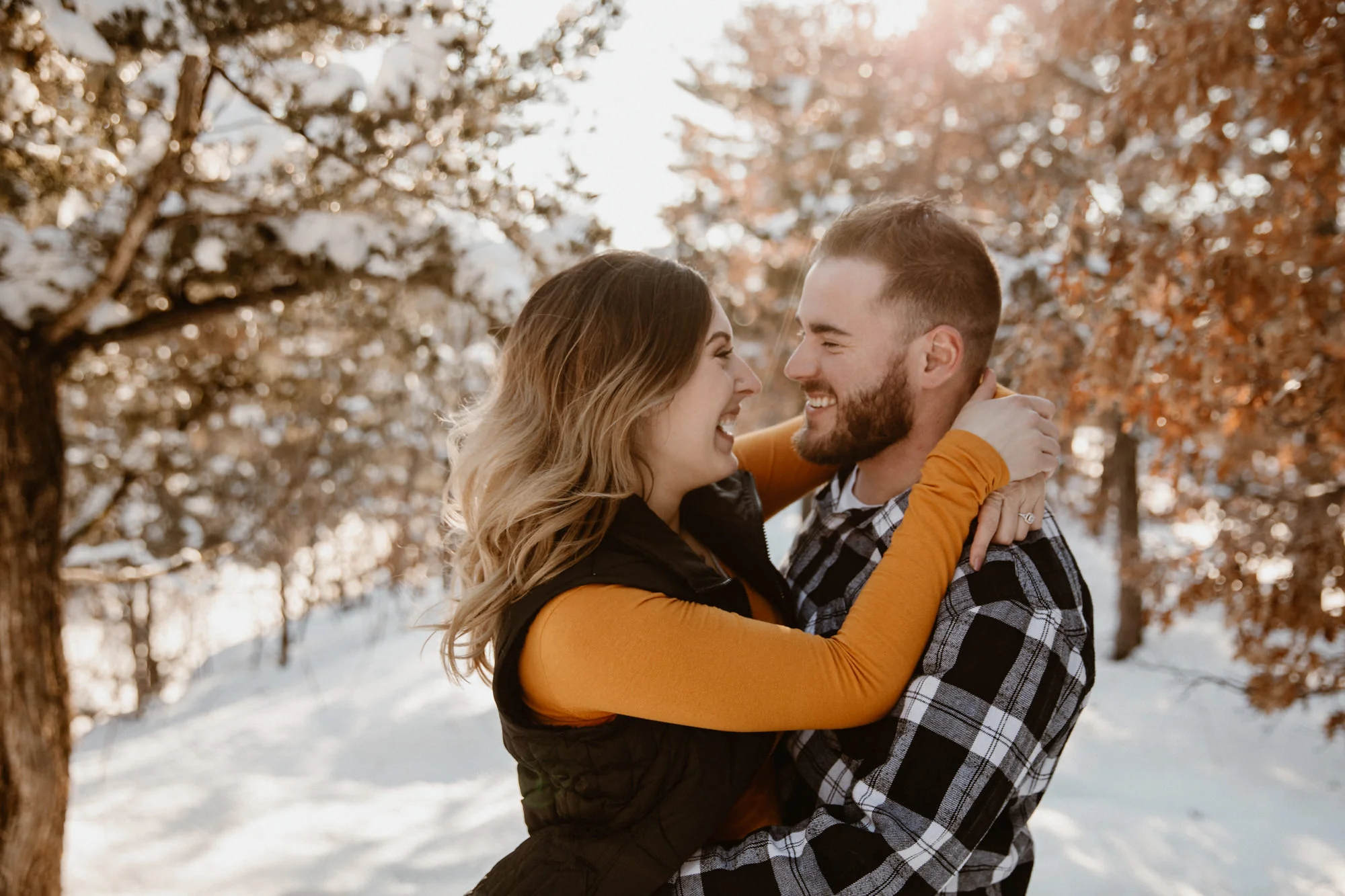 Wisconsin couple laughing in the woods at sunset.