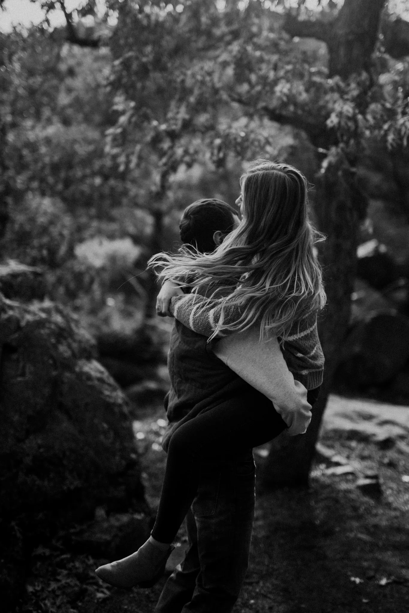 Moody black and white image of Wisconsin couple spinning in the woods.