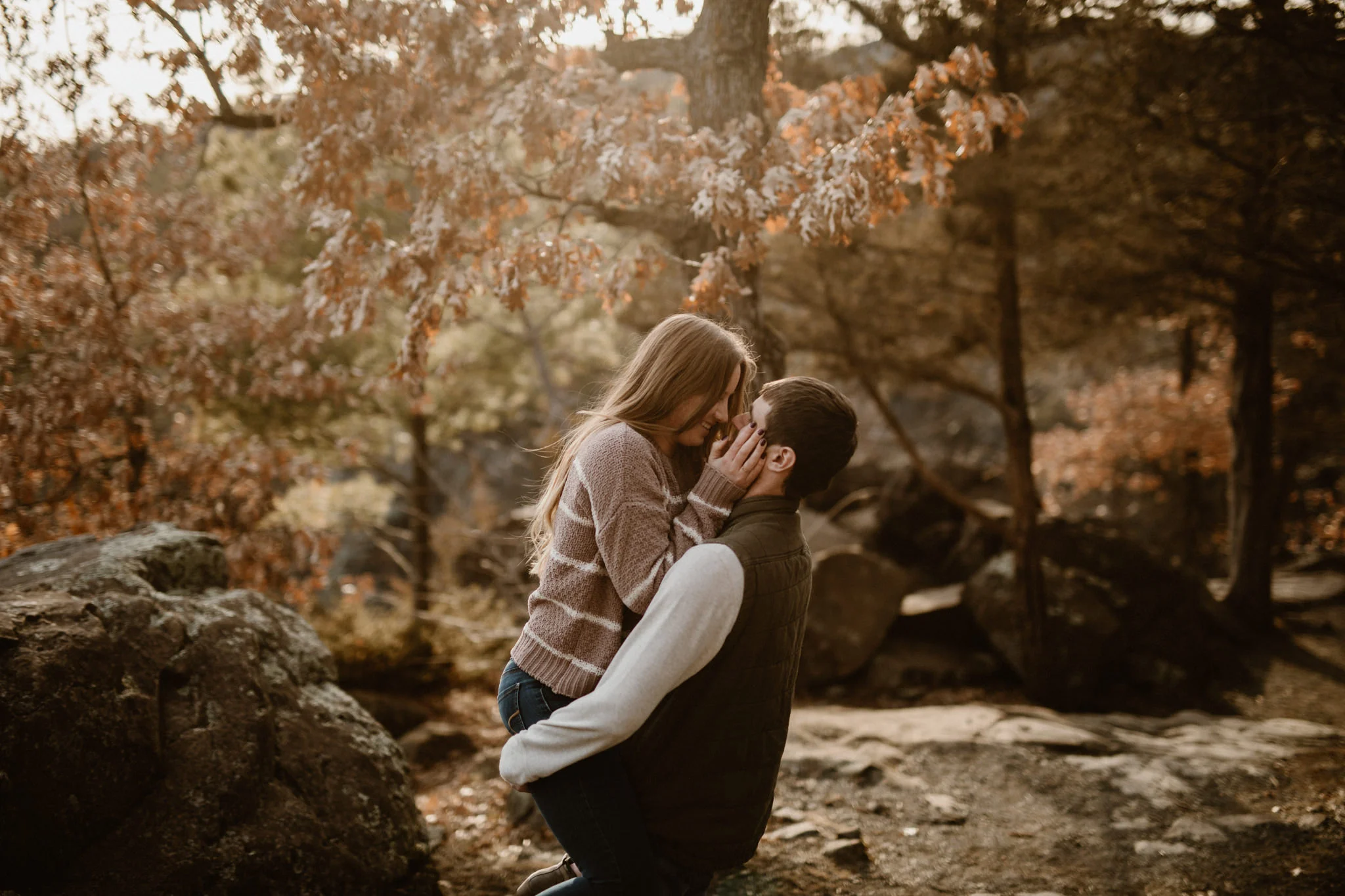 Image of a couple in the woods of Wisconsin, he picked her up and they are about to kiss.