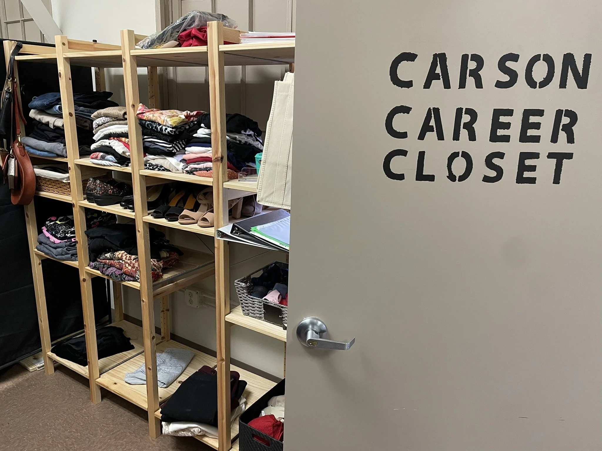 Open door stating "Carson Career Closet." Room with shelf full of folded office-appropriate clothes.