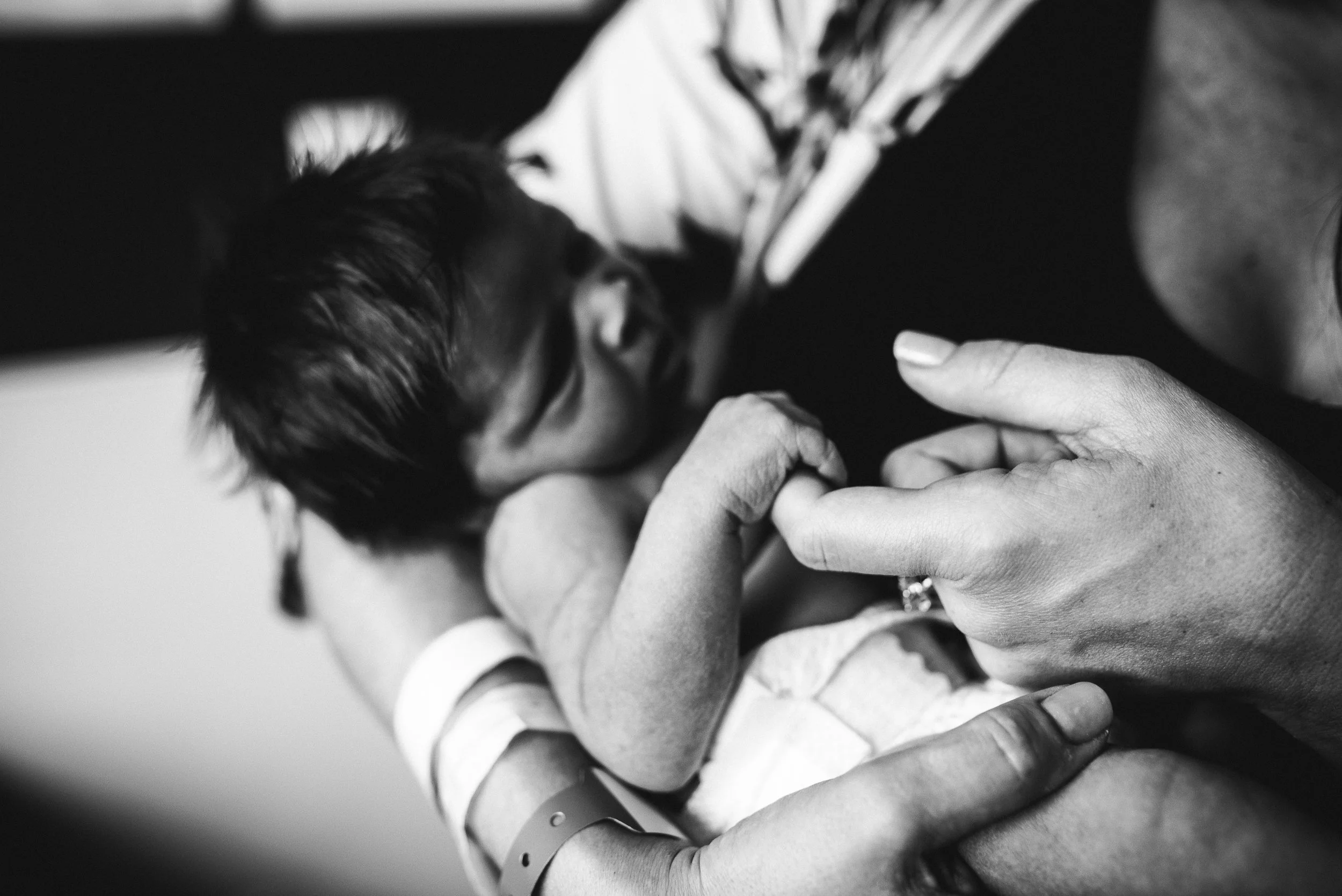 mom holing newborn finger