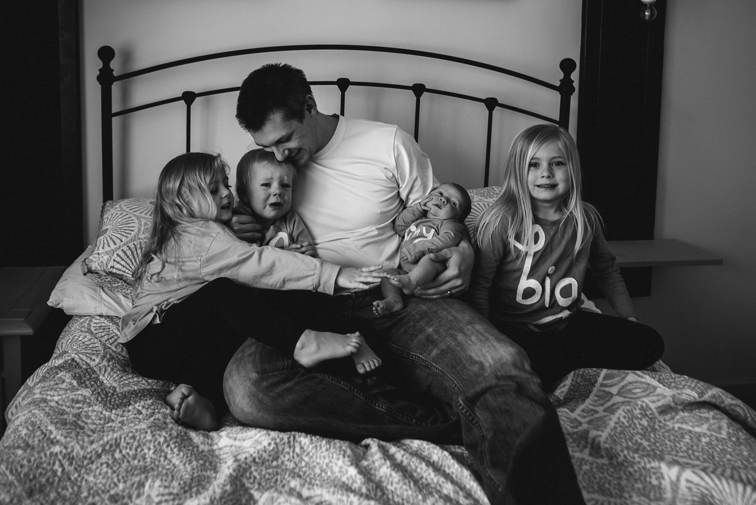 dad with daughters on bed