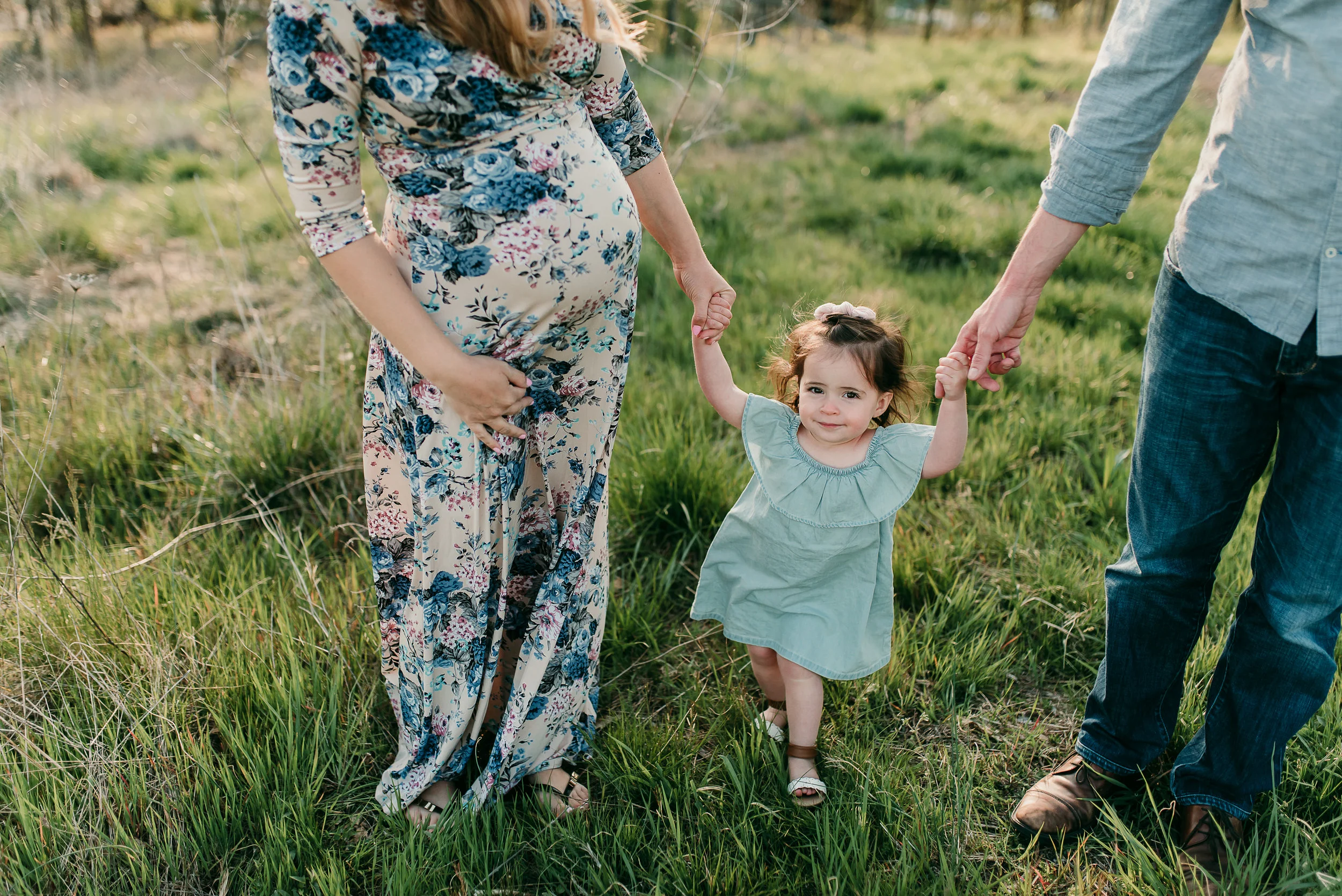 family walking through field holding hands