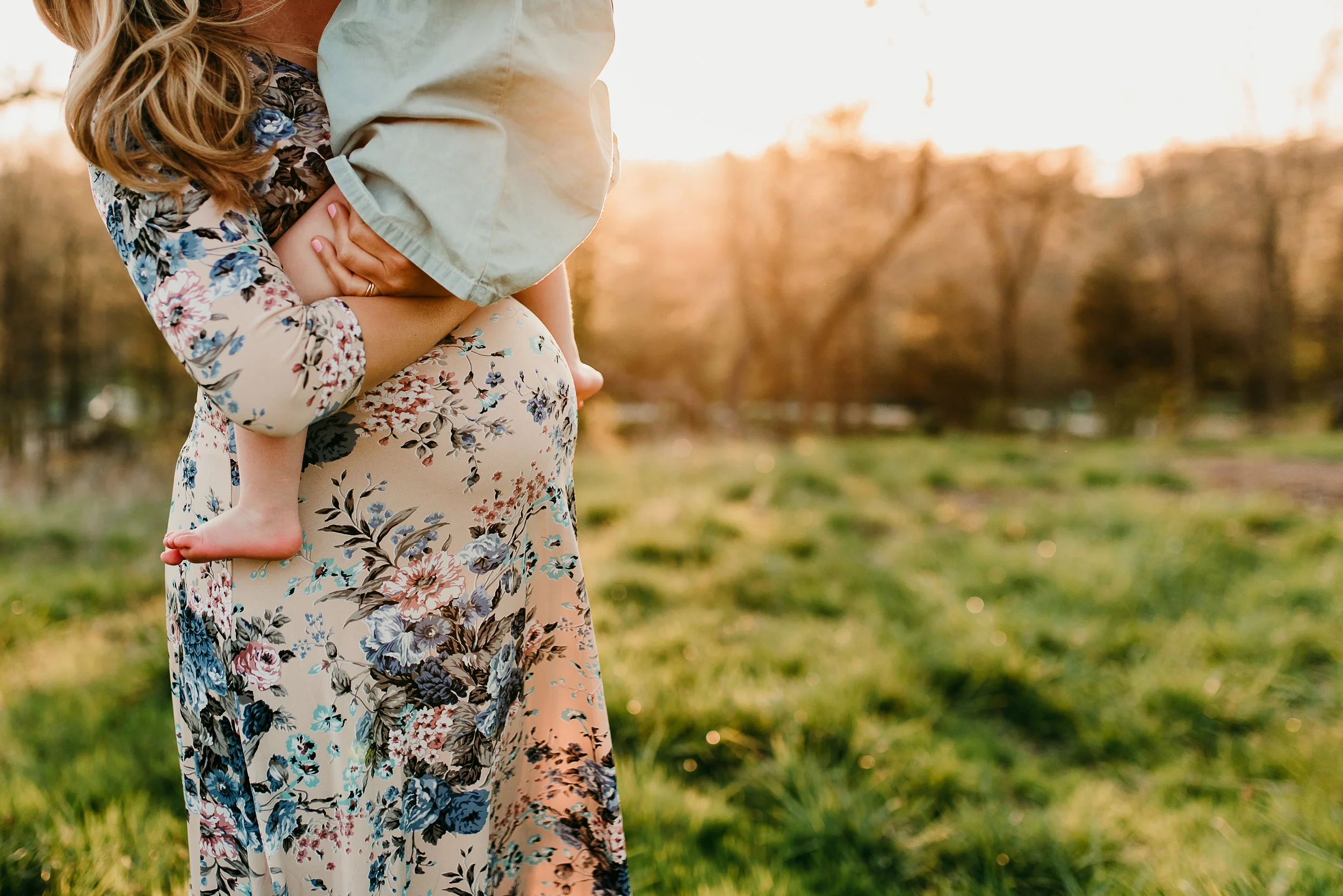 mom holding daughter on pregnant belly
